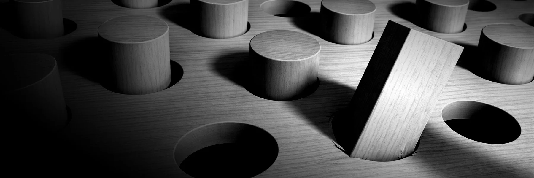 Grayscale image of a wooden board with round pegs in holes and one square peg in a round hole.
