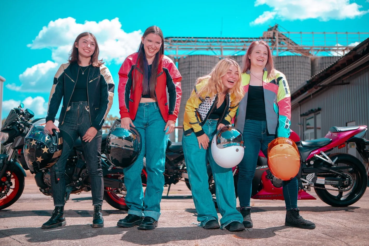 4 women in motorcycle gear outside laughing