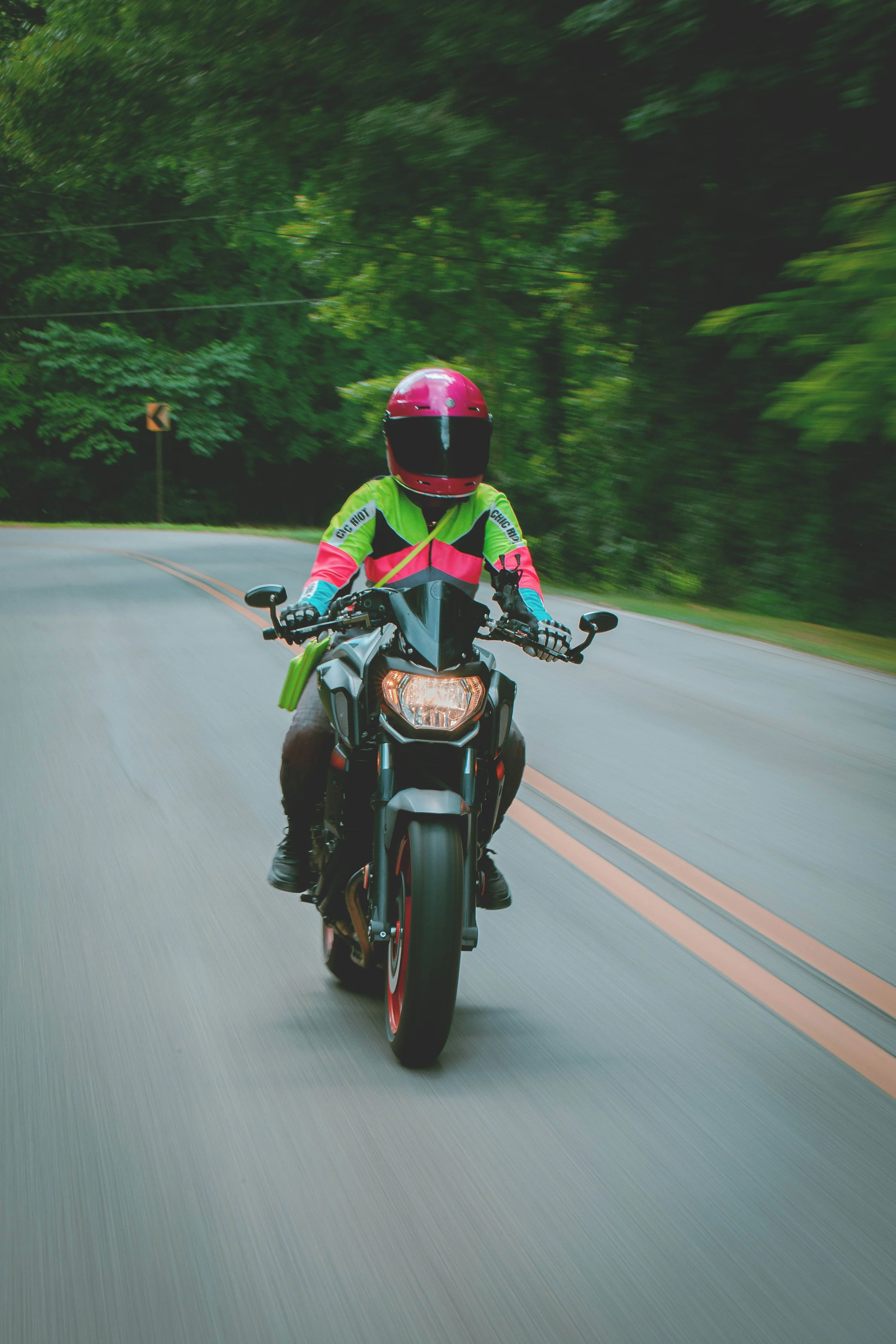 Women riding a motorcycle on back country road.