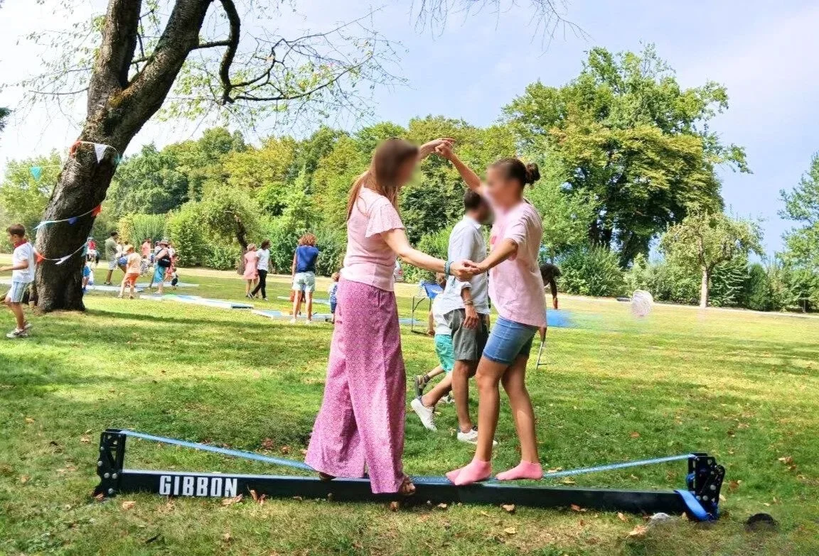 Supervised slackline initiation for adults in a natural setting, organized by Slackline Events during a festive day.