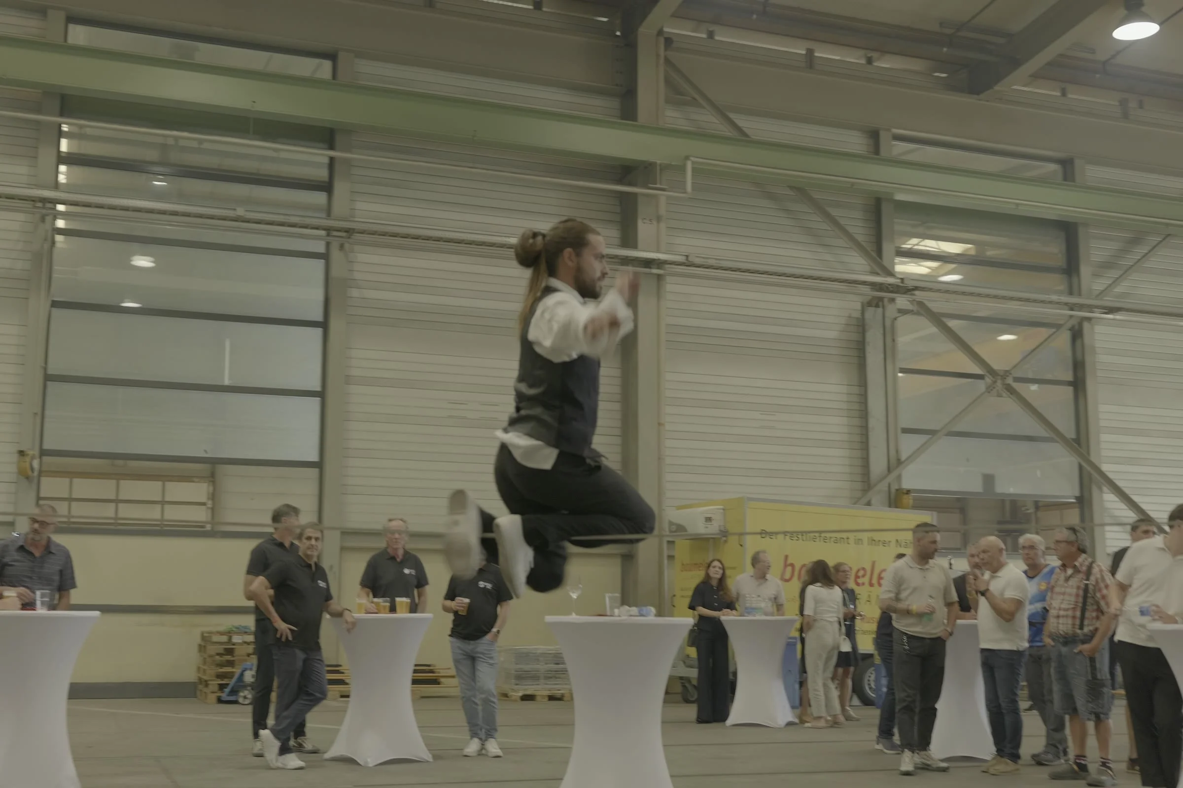 Artiste de slackline en saut groupé au-dessus de la ligne, entouré des collaborateurs de Condecta lors de l'inauguration du site de Wikon