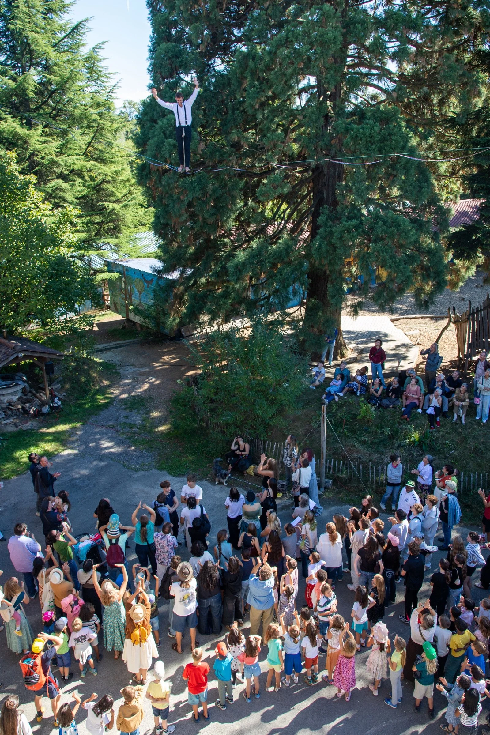 Enfants et familles lèvent les bras sous la highline pendant la fête des 50 ans de l'École Steiner de Lausanne
