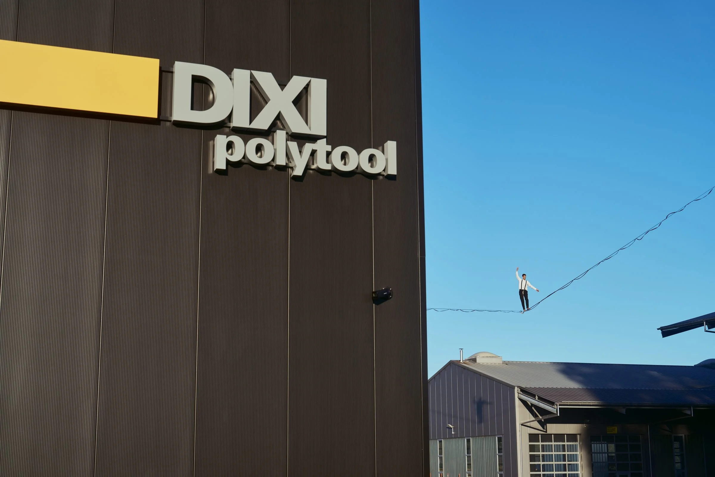 Highliner sur une ligne tendue à côté du logo DIXI Polytool sur la façade du nouveau bâtiment de Gampelen
