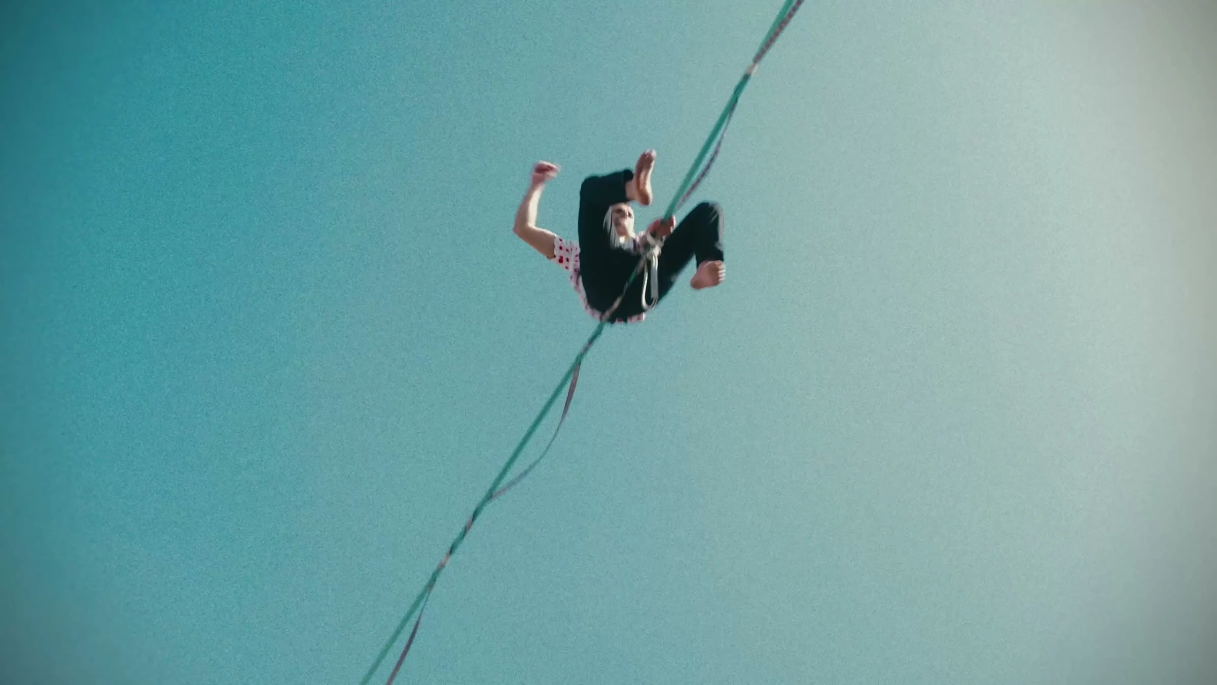 Artiste en maillot à pois rouges pendant une figure sur la highline de Thonon-les-Bains, vu d'en dessous