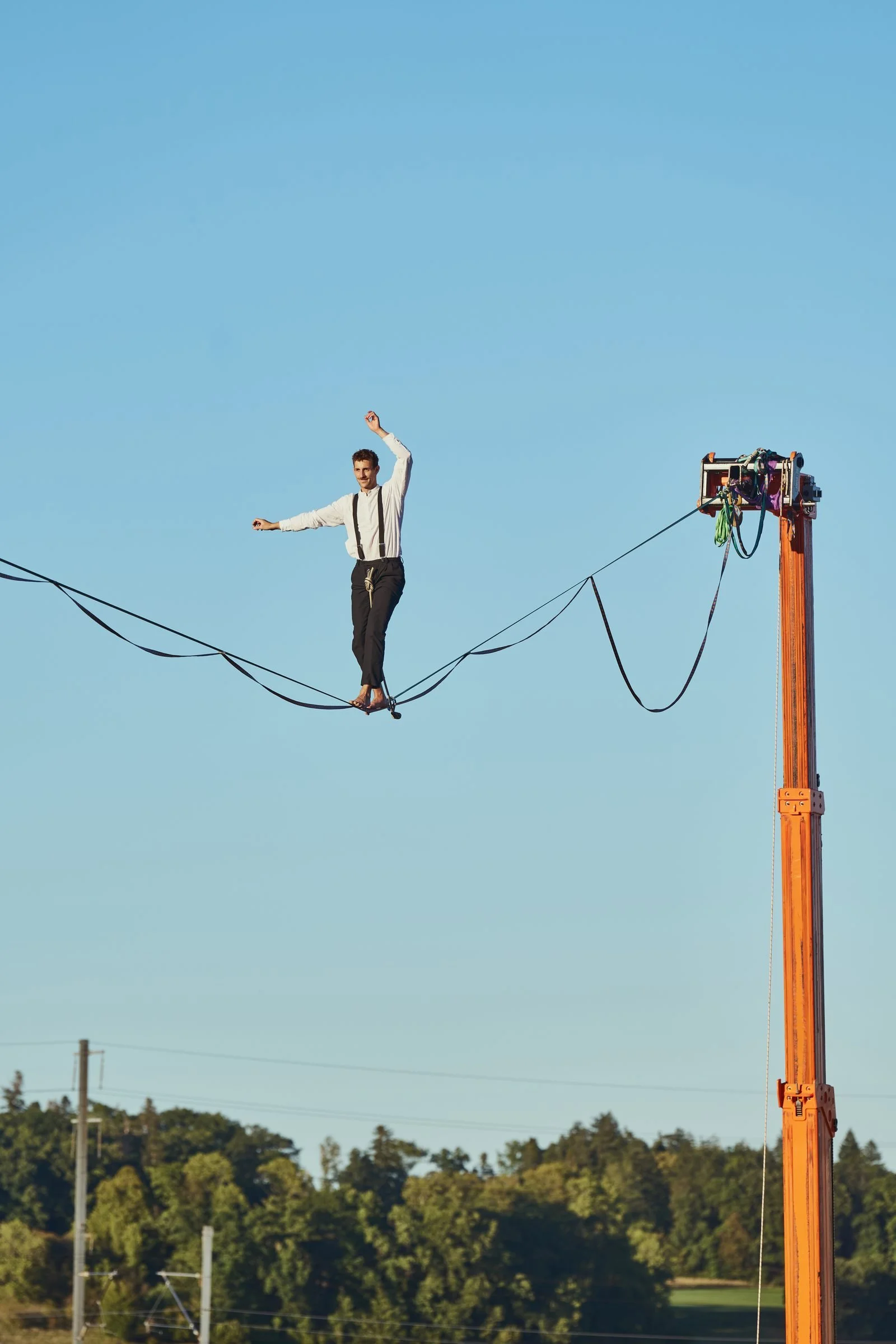 Highline ancrée sur une nacelle télescopique orange pendant un spectacle d'entreprise à Gampelen