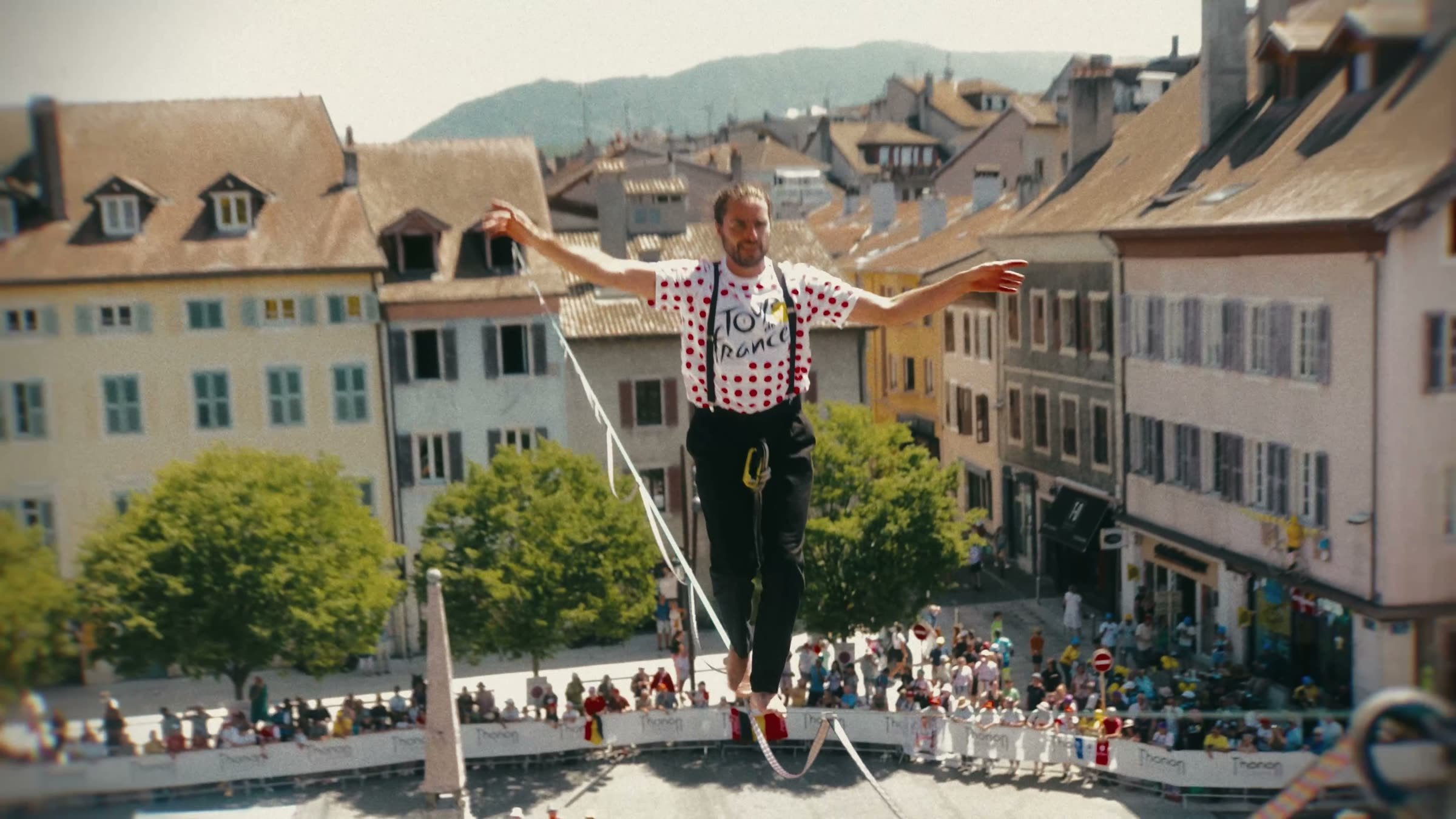 Artiste de highline en maillot à pois au-dessus de la place de l'Hôtel de Ville de Thonon-les-Bains pendant le Tour de France