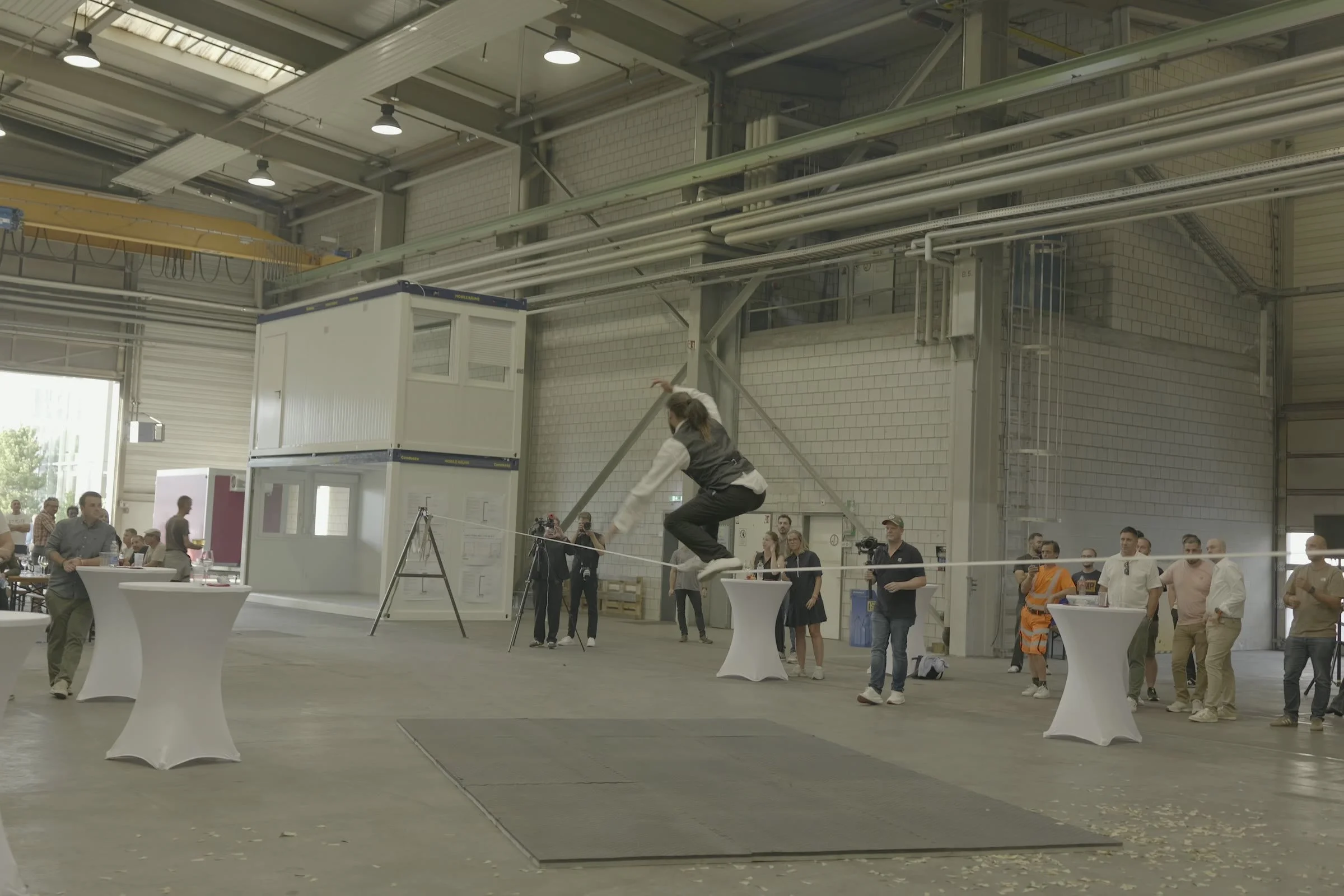 Slackline relevée par un chevalet (A-frame) à côté d'un module Condecta, dans une halle industrielle à Wikon