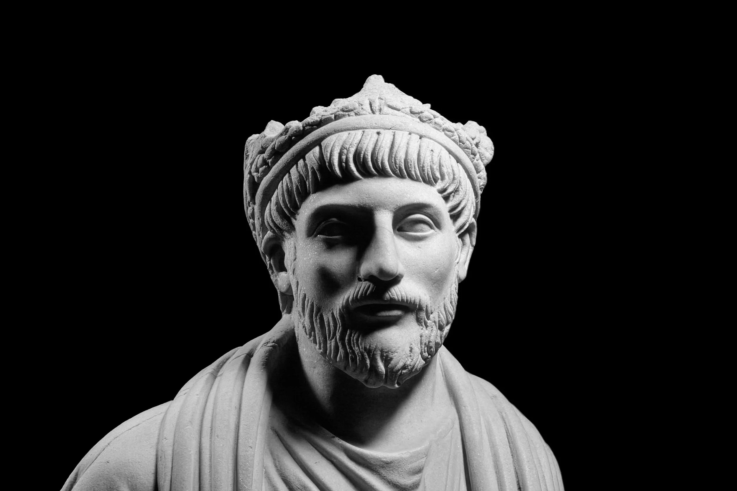 Marble statue long identified as Julian the Apostate, now often interpreted as a priest of Sarapis, shown as a bearded late Roman figure against a black background.