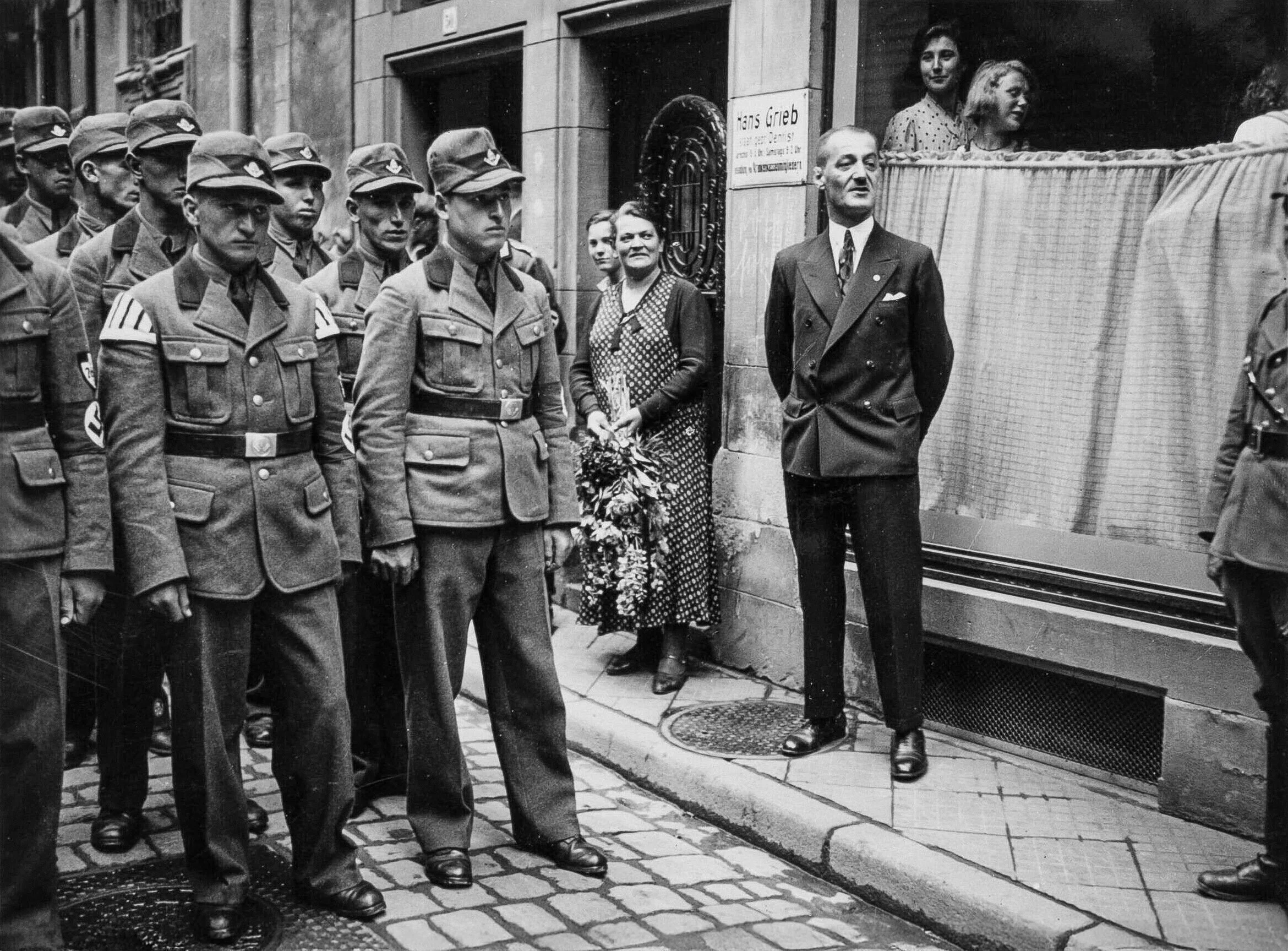 Oskar Dirlewanger standing in civilian clothing in Heilbronn in 1937, shortly after his release from Welzheim Prison, with uniformed SA men and local onlookers present.