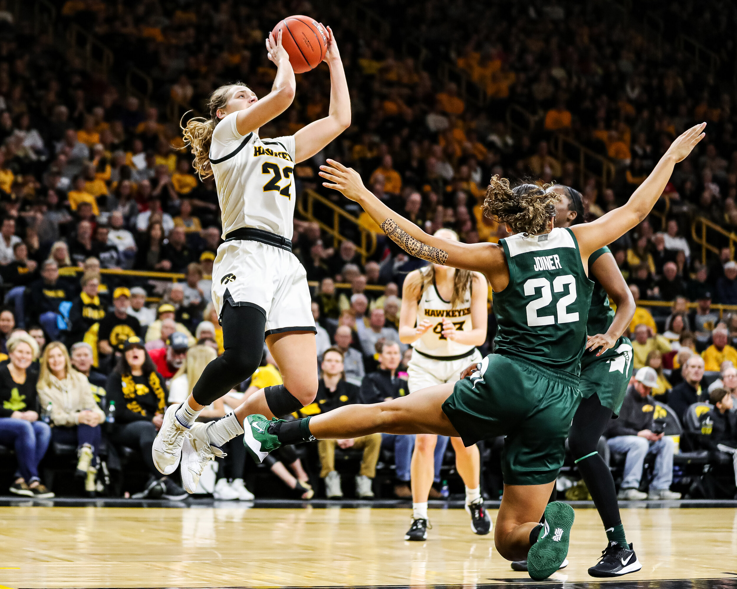  Iowa guard Kathleen Doyle (22) sends Michigan State guard Moira Joiner (22) flying backwards as Doyle launches a shot during a basketball game against Michigan State University at Carver-Hawkeye Arena in Iowa City, on Sunday, Jan 26, 2020.  
