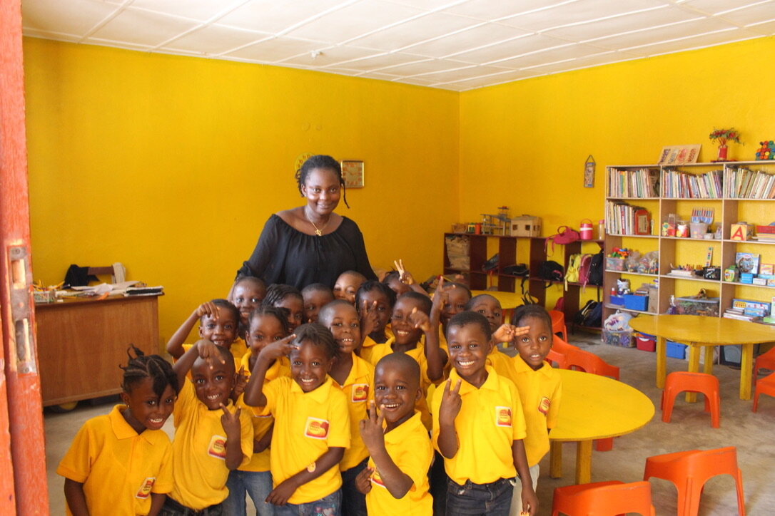 Young students with teacher in yellow classroom giving the V sign