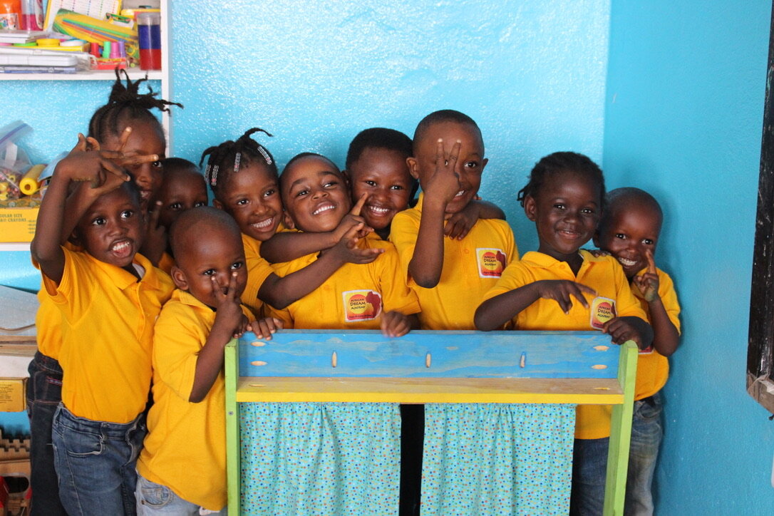 Close-up of 10 young students standing behind a puppet theater