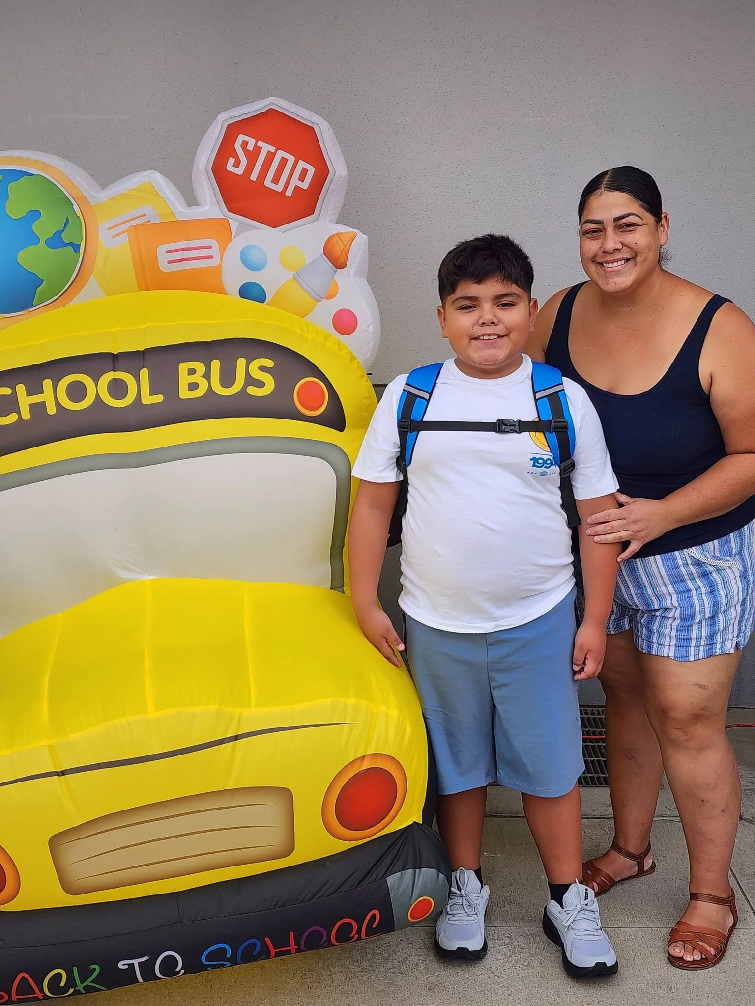 An adult and student smile beside the school-bus display.