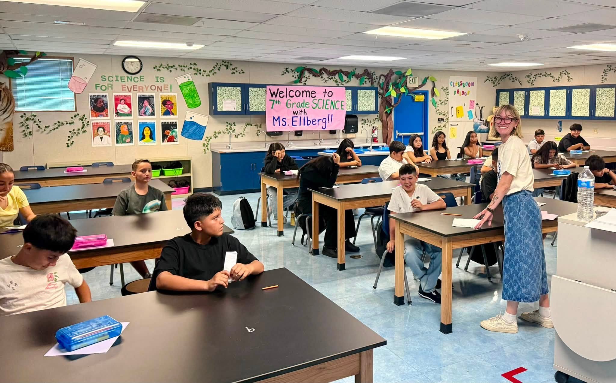 A teacher welcomes students to a seventh-grade science classroom.