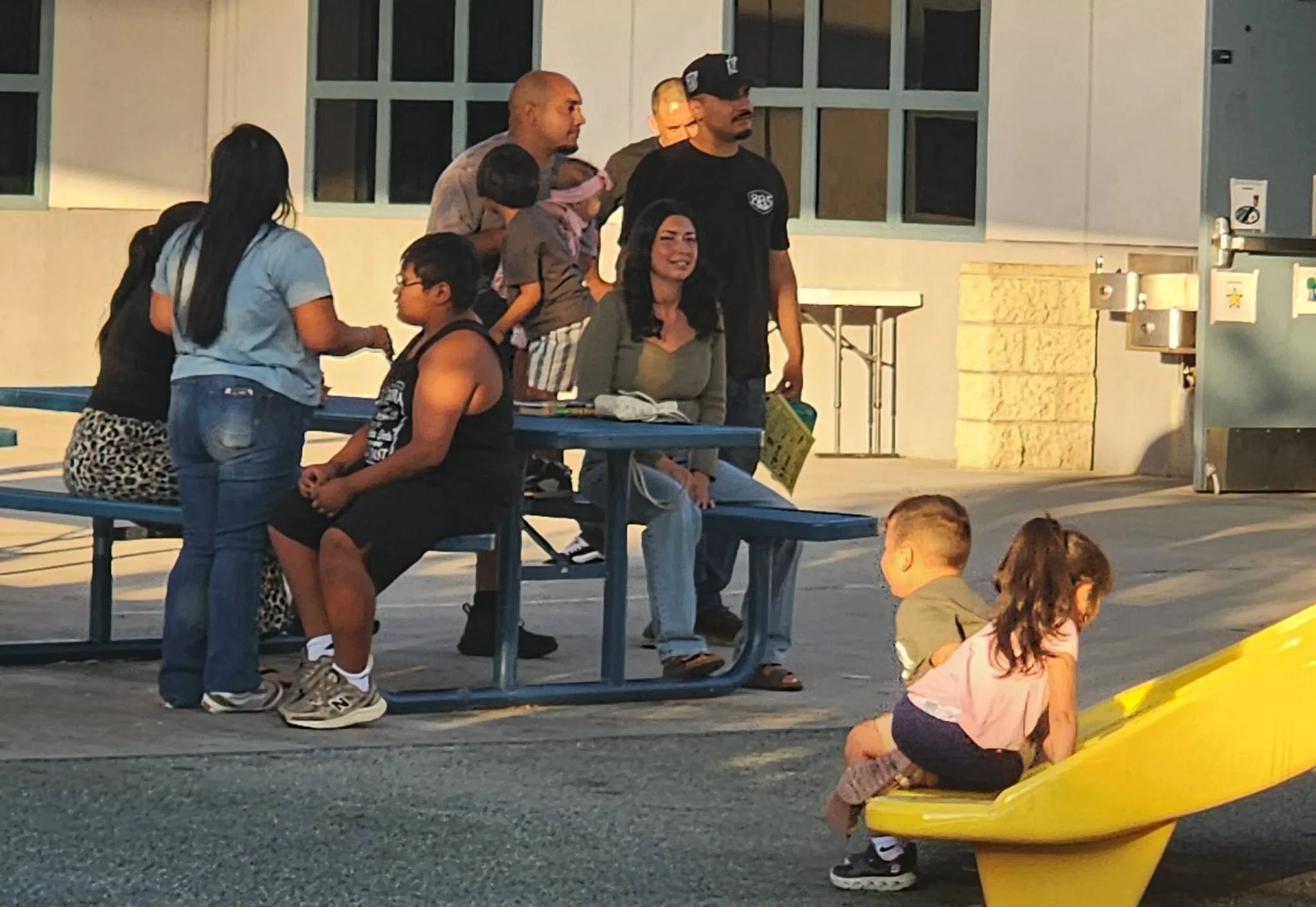 Wildcat families gather on the Mountain Vista playground while children play on a slide.