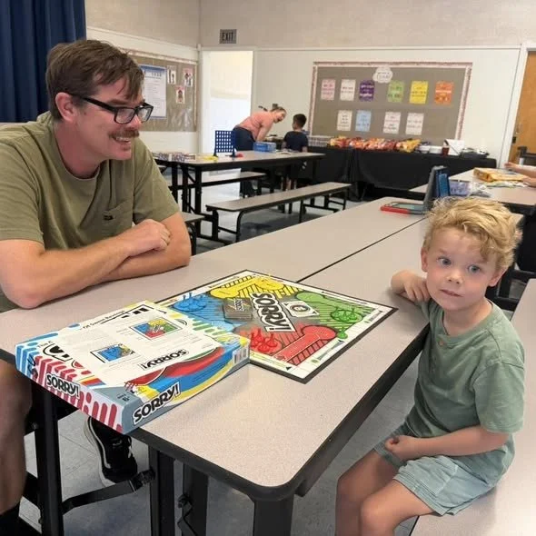 A student and family member play a board game at San Cayetano Family Game Night.