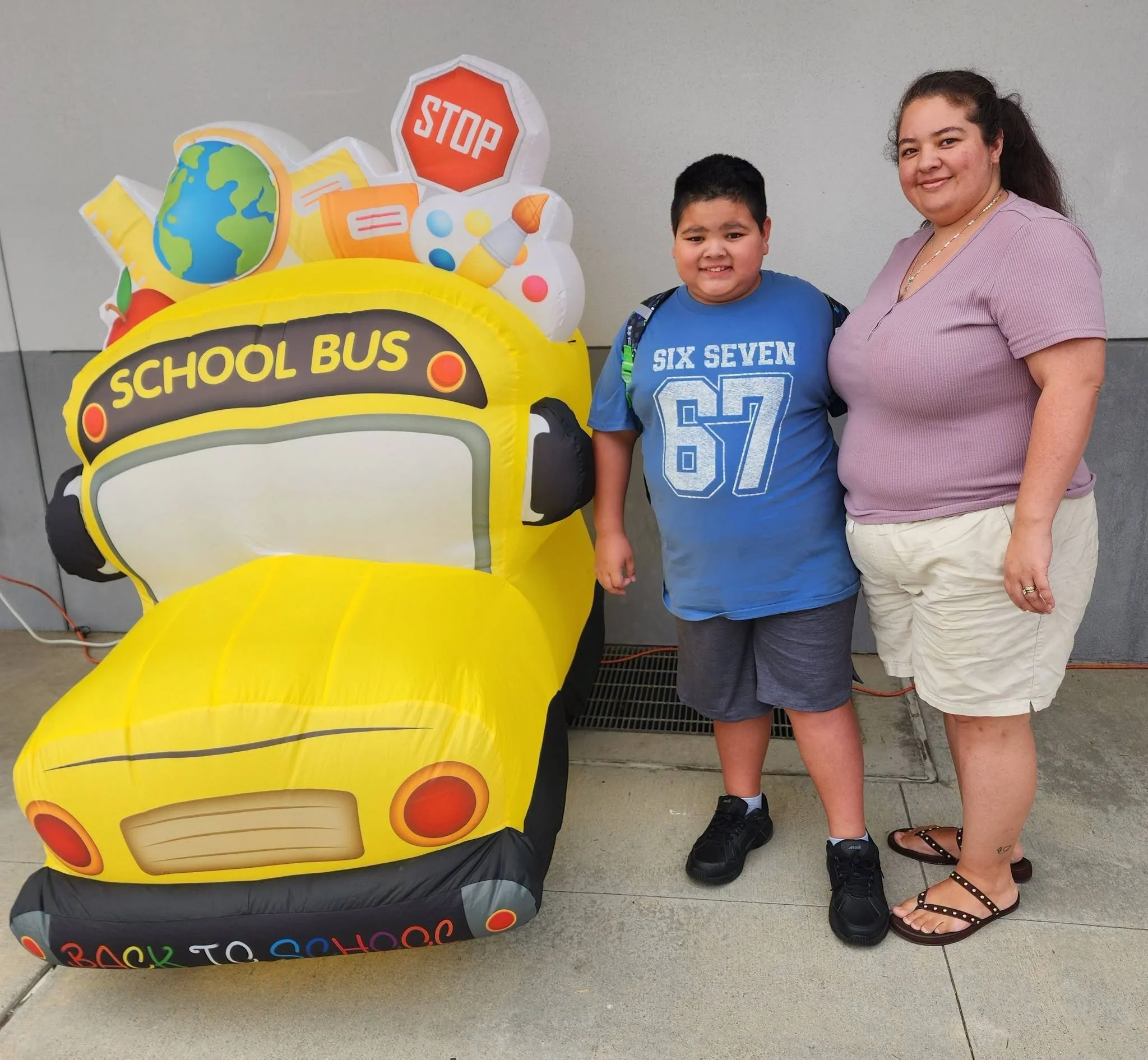An adult and student pose beside the school-bus welcome decoration.