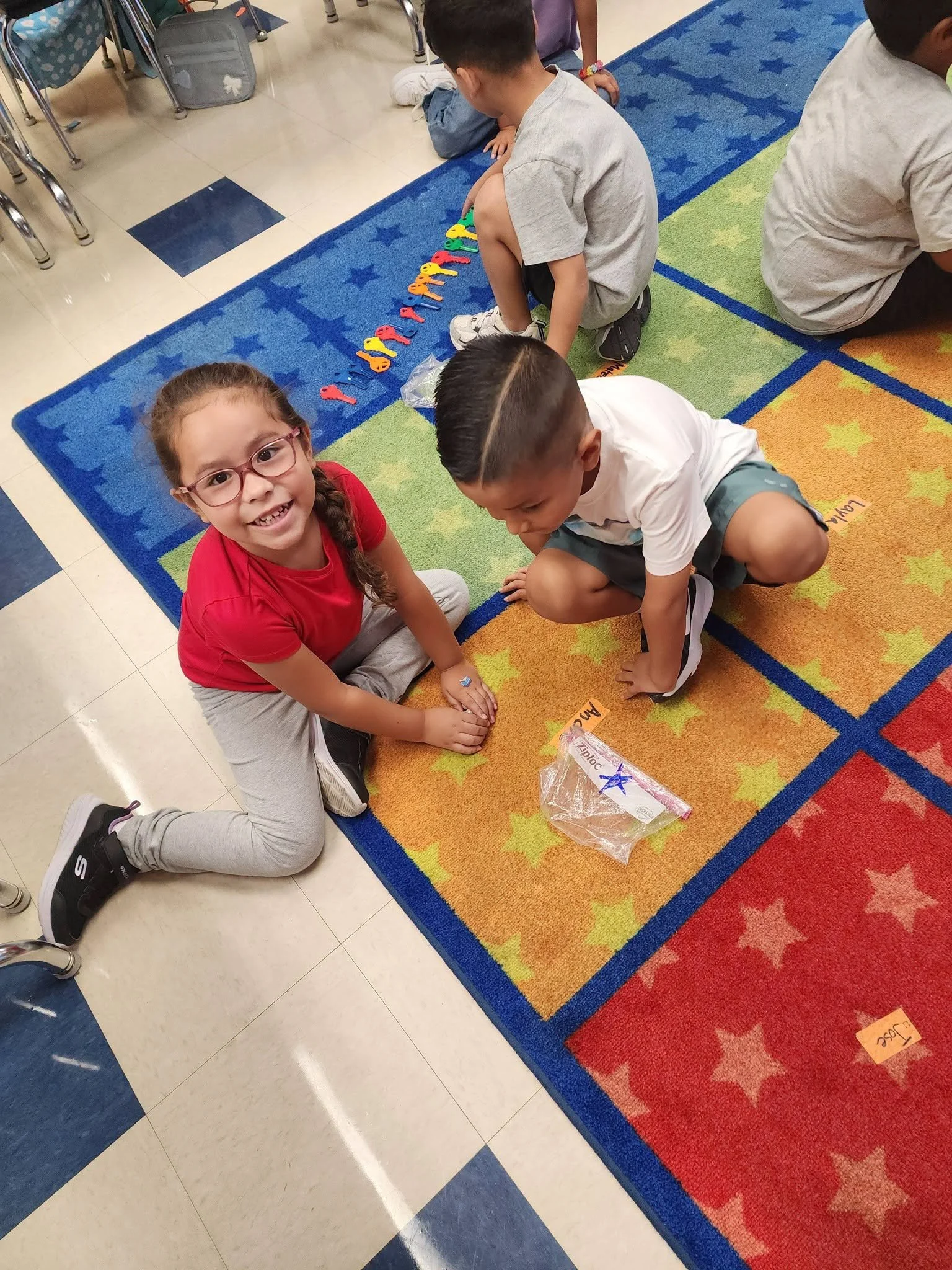 Kindergarten classmates work together on the colorful classroom rug with counting materials.