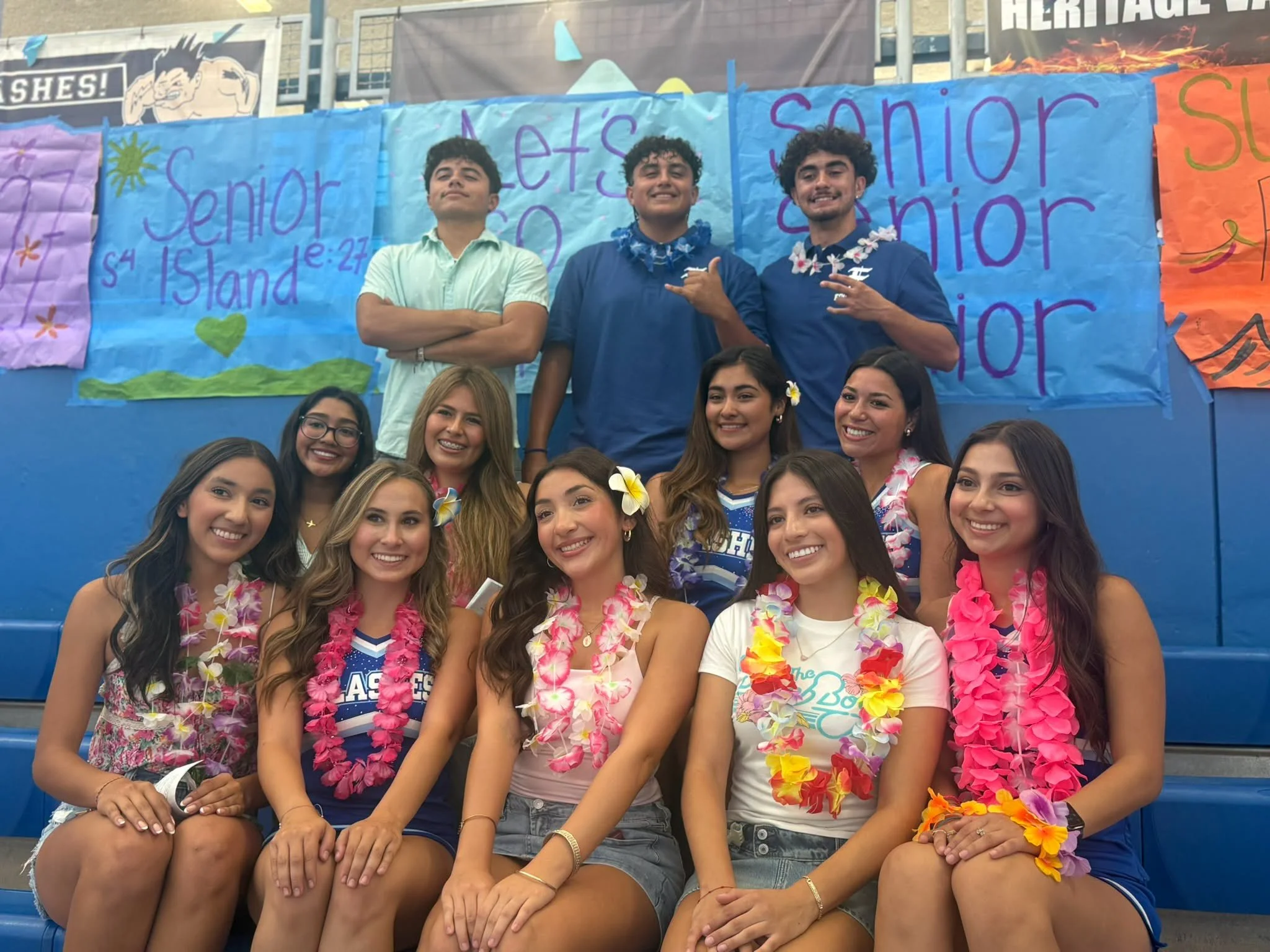 Fillmore High students and cheerleaders wearing flower leis pose in front of senior spirit posters.