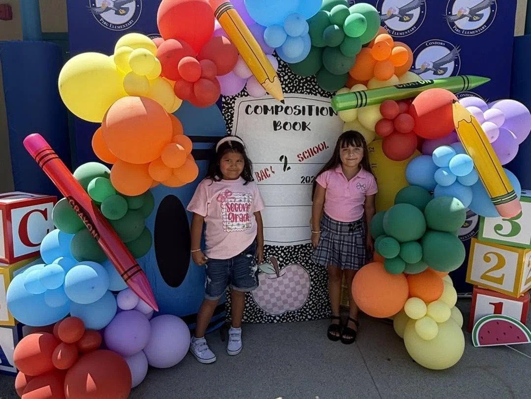 Two students pose beside the composition-book and balloon display.