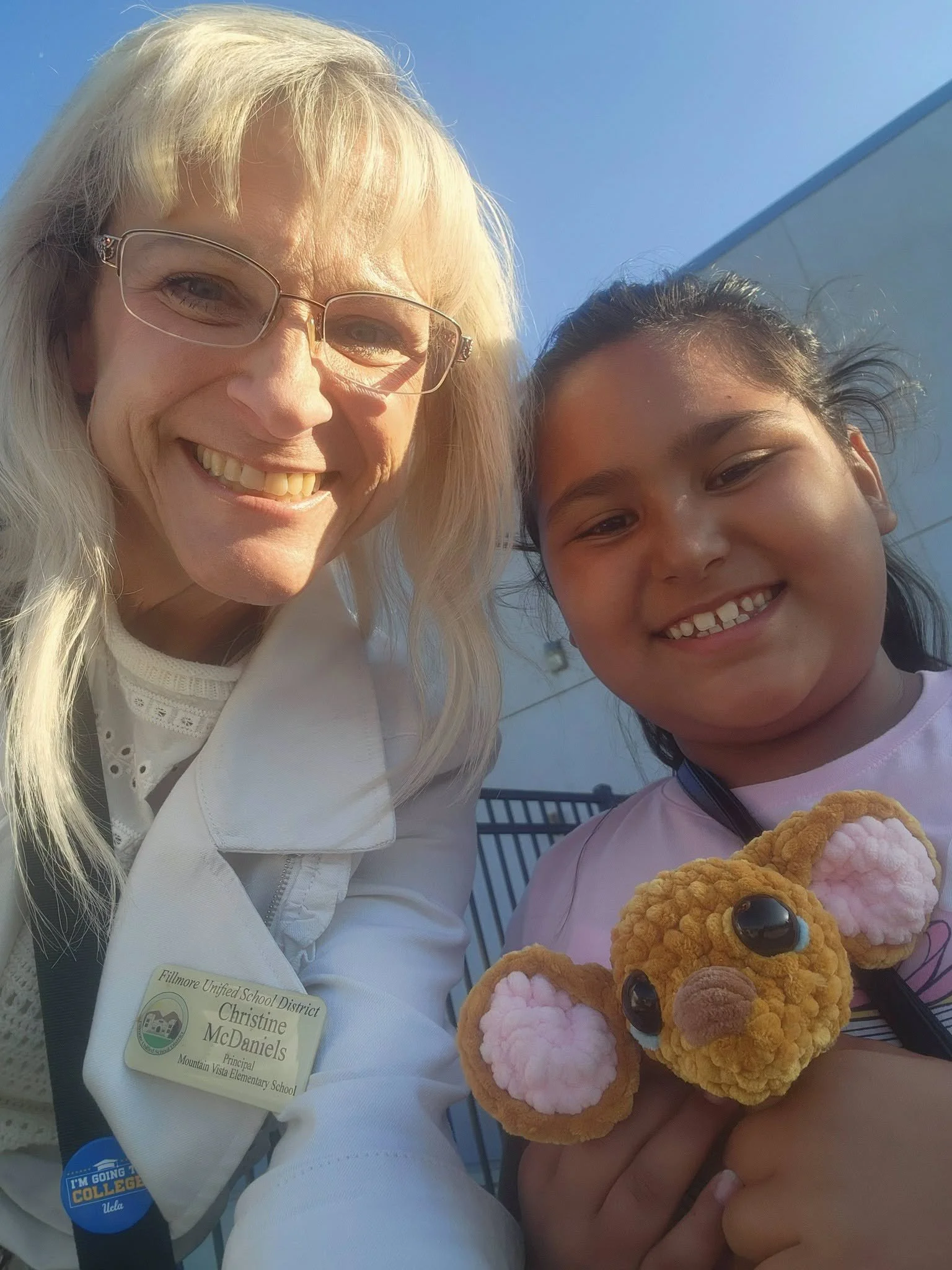 The Mountain Vista principal smiles with a student holding a stuffed animal.