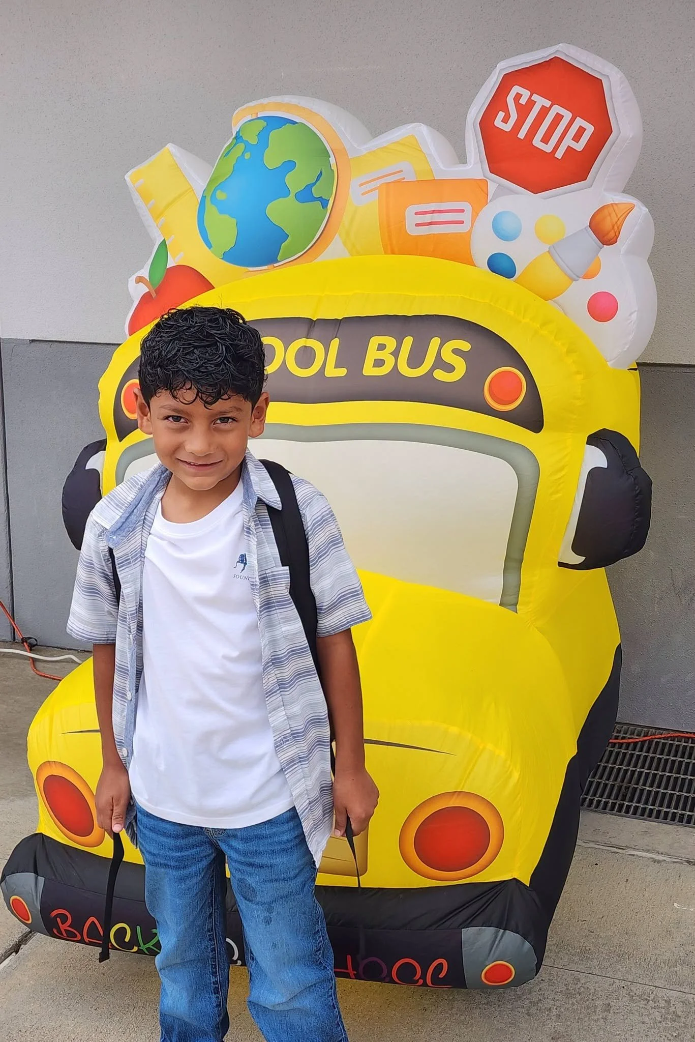 A smiling student stands in front of the welcome school-bus display.