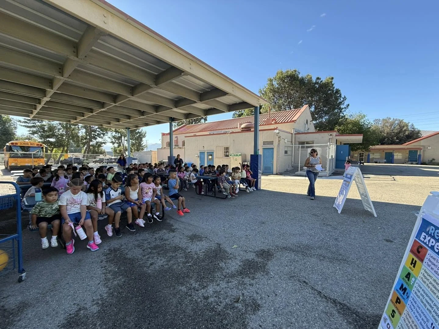 Students learn campus expectations while seated under an outdoor shelter.