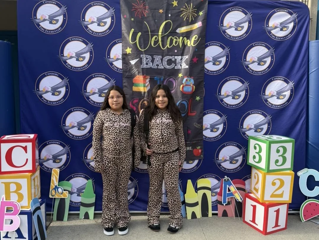 Two students in matching outfits pose at a welcome-back display.