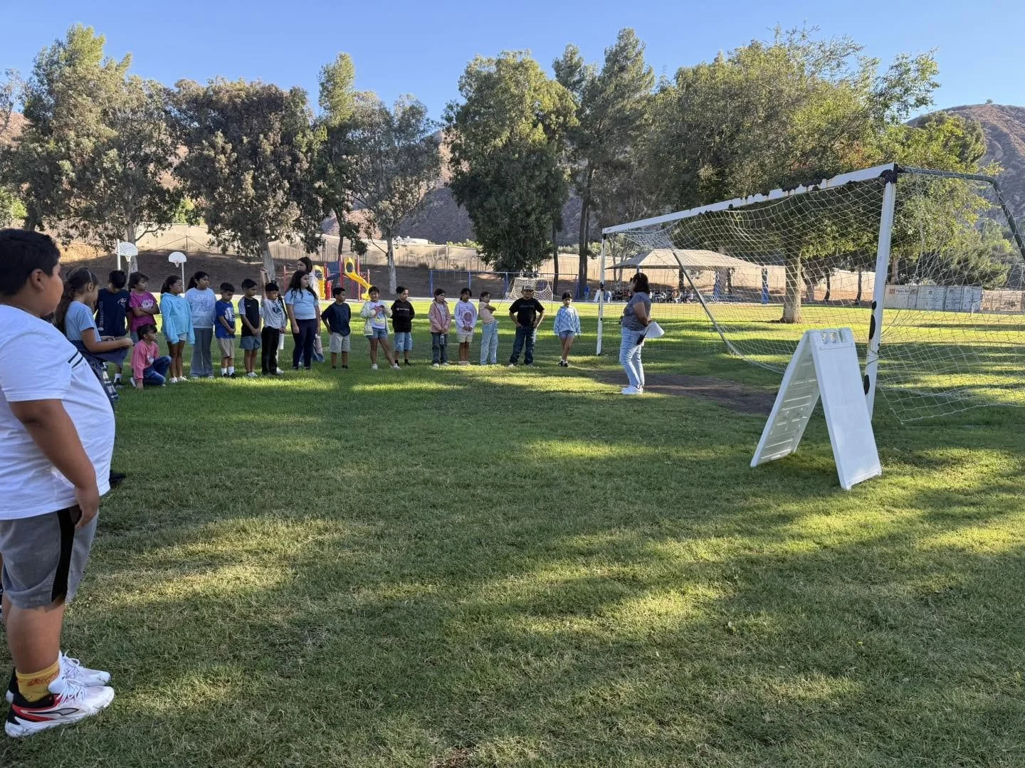 Students gather by the soccer goal to learn field expectations.