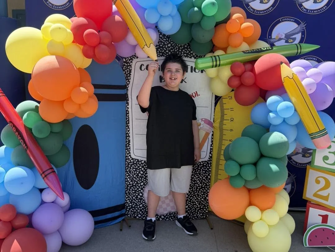 A student smiles beneath the back-to-school balloon arch.