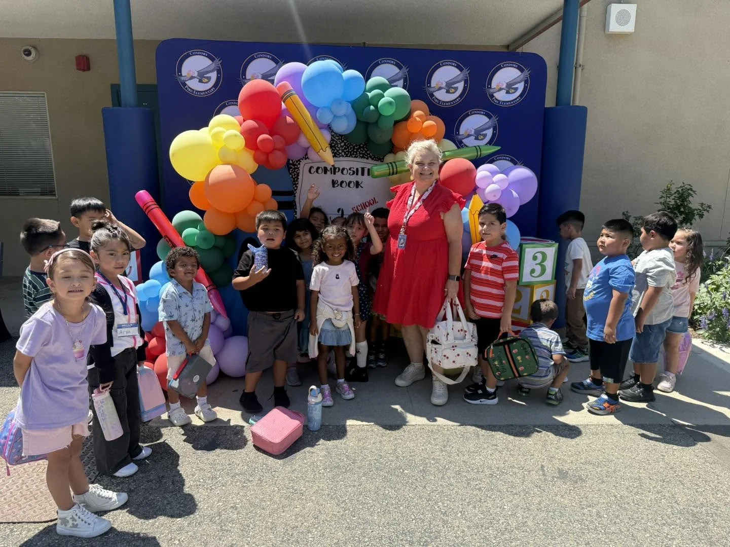 A teacher and students gather at the welcome balloon display.