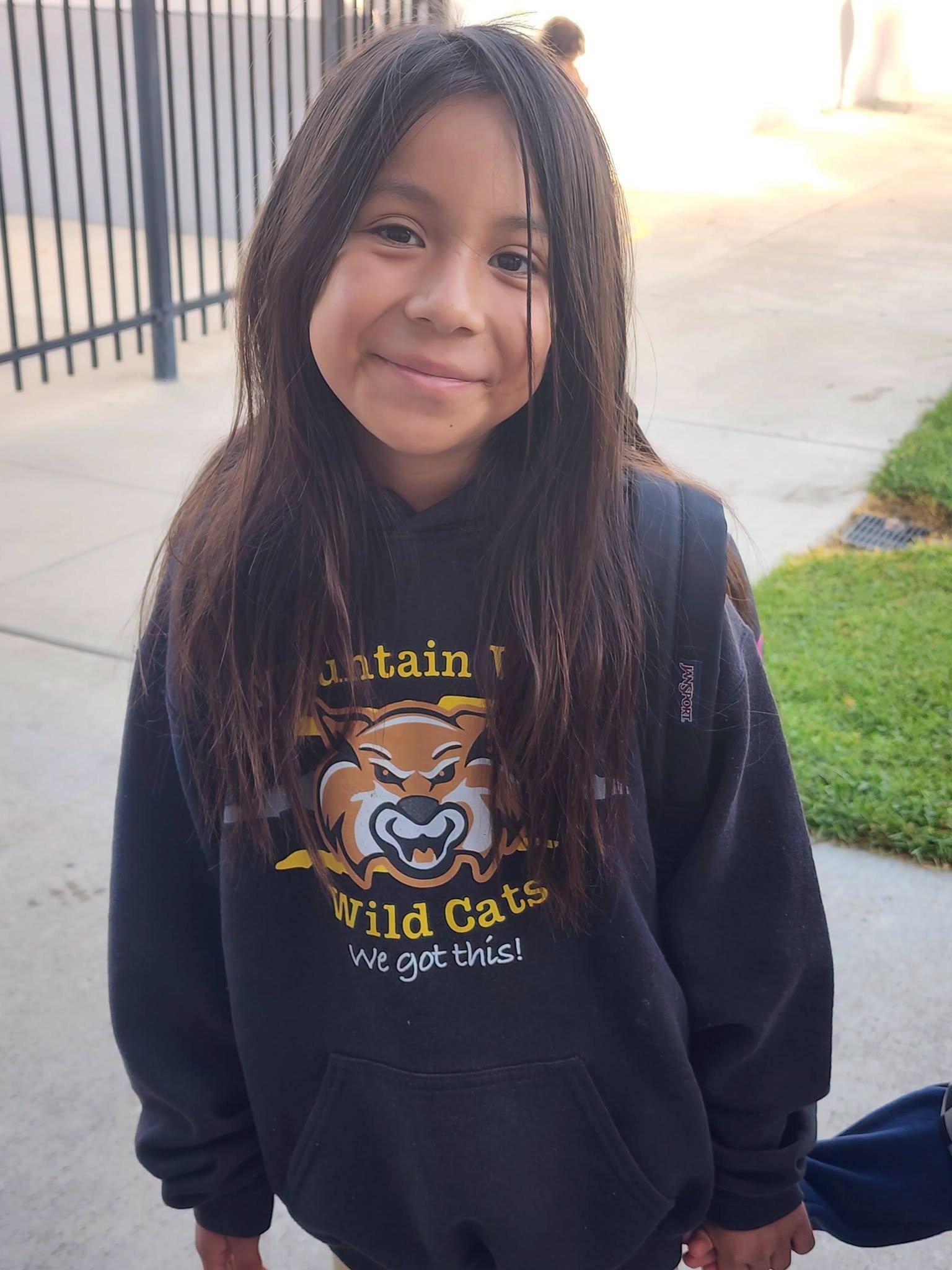 A smiling student wears a Mountain Vista Wildcats sweatshirt outdoors.