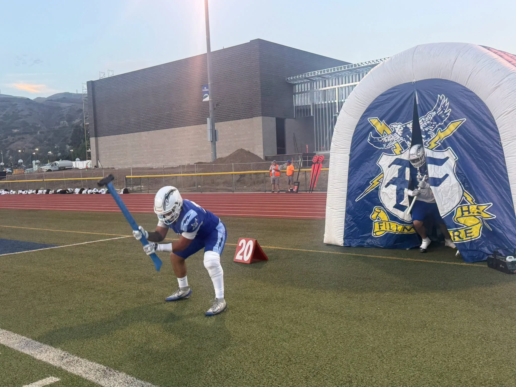 A Flashes football player enters the field beside a blue-and-white Fillmore High inflatable tunnel.