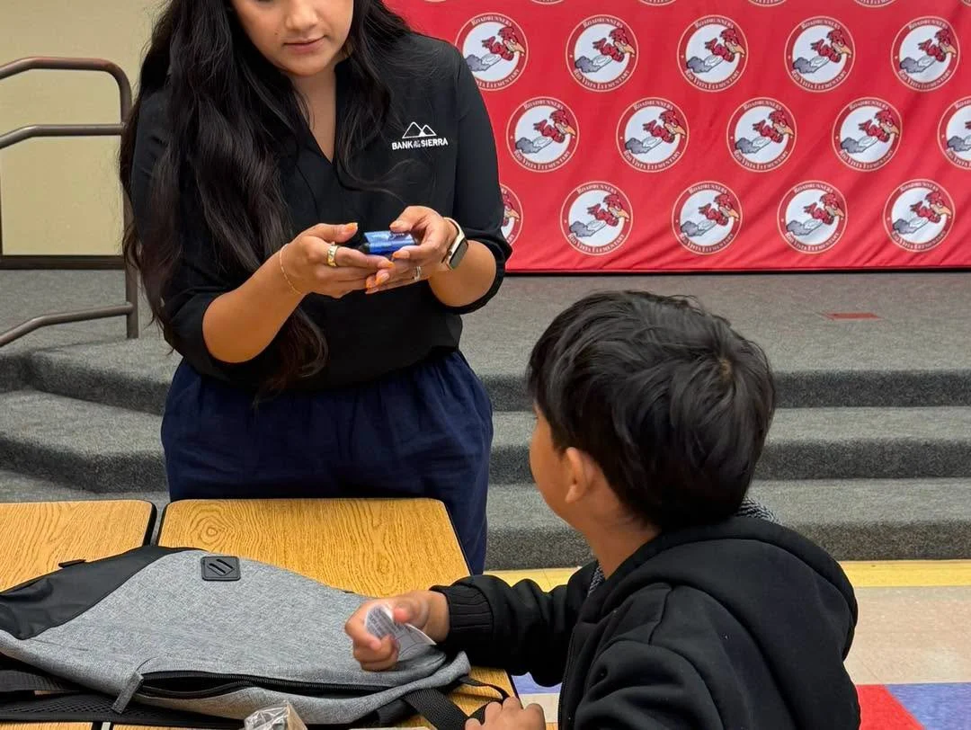 A bank representative shows a donated item to a student.