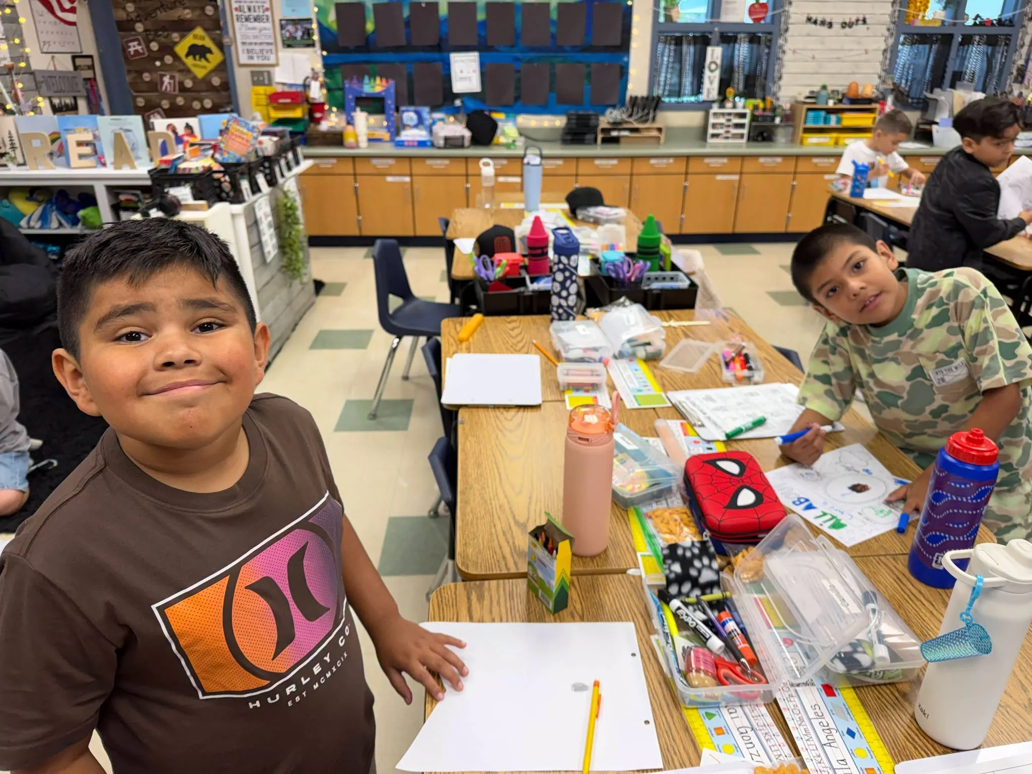 Students draw and color at desks stocked with school supplies.