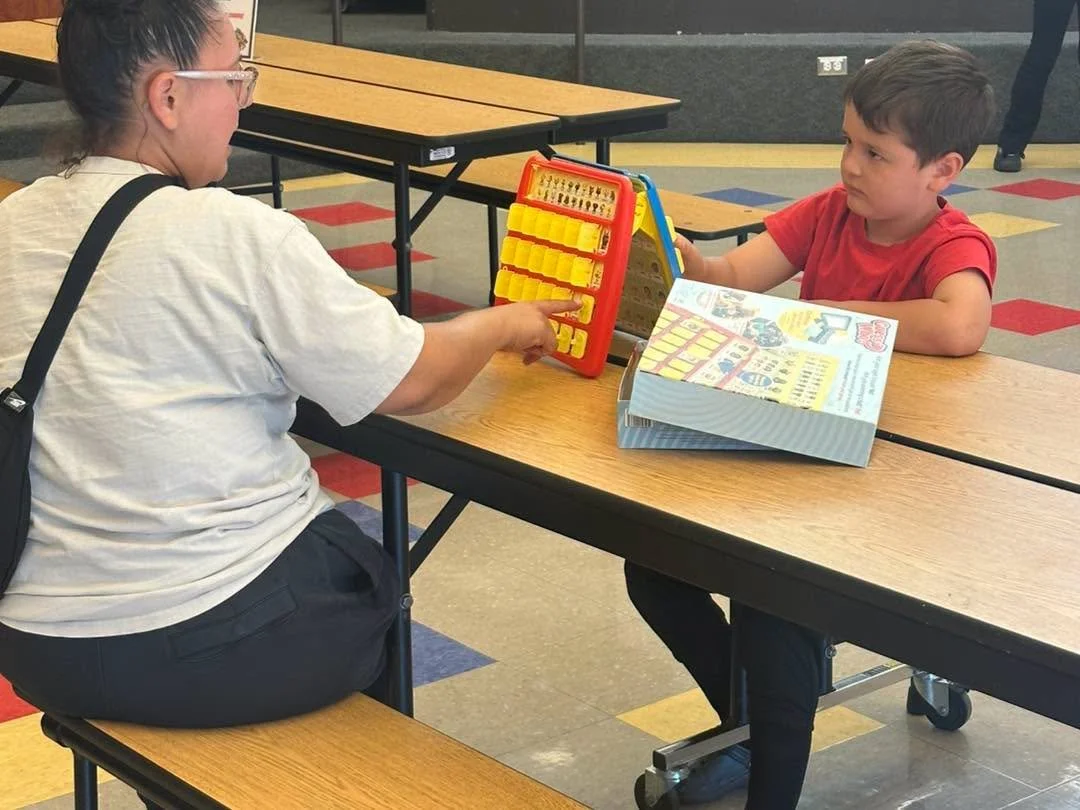 An adult and child play Guess Who at a table.