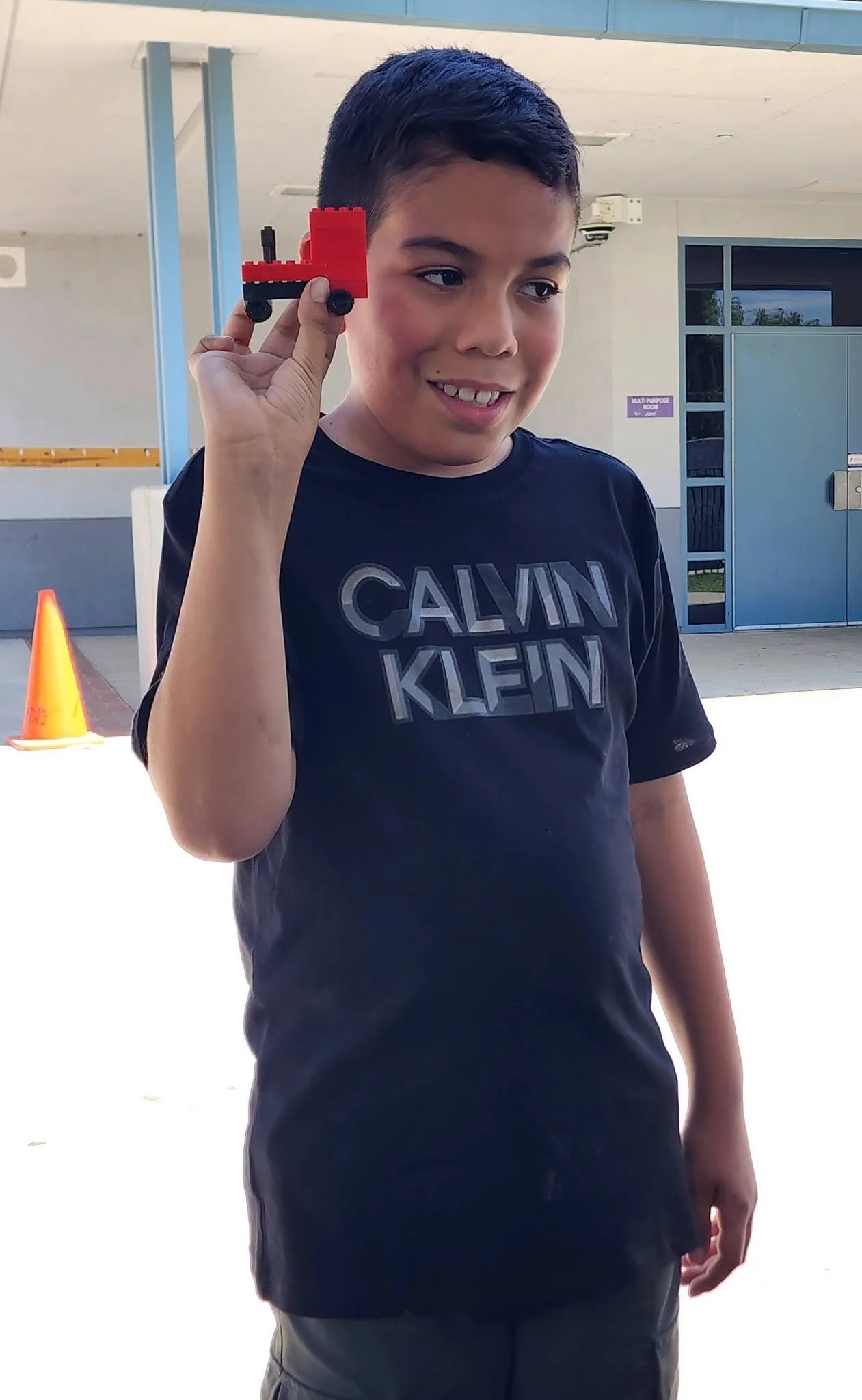 A student holds up a small red Lego vehicle.