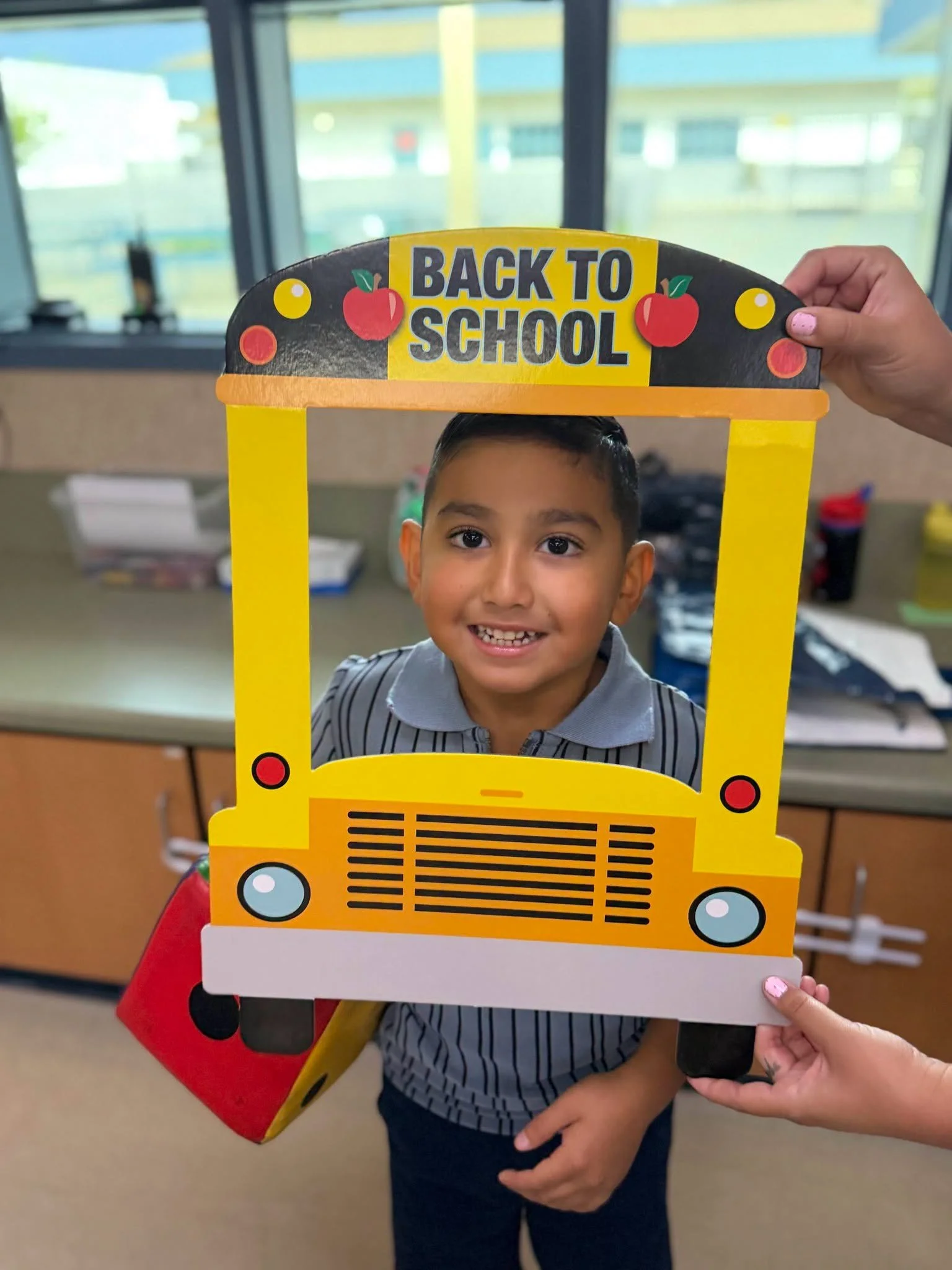 A smiling student poses through the back-to-school bus frame.