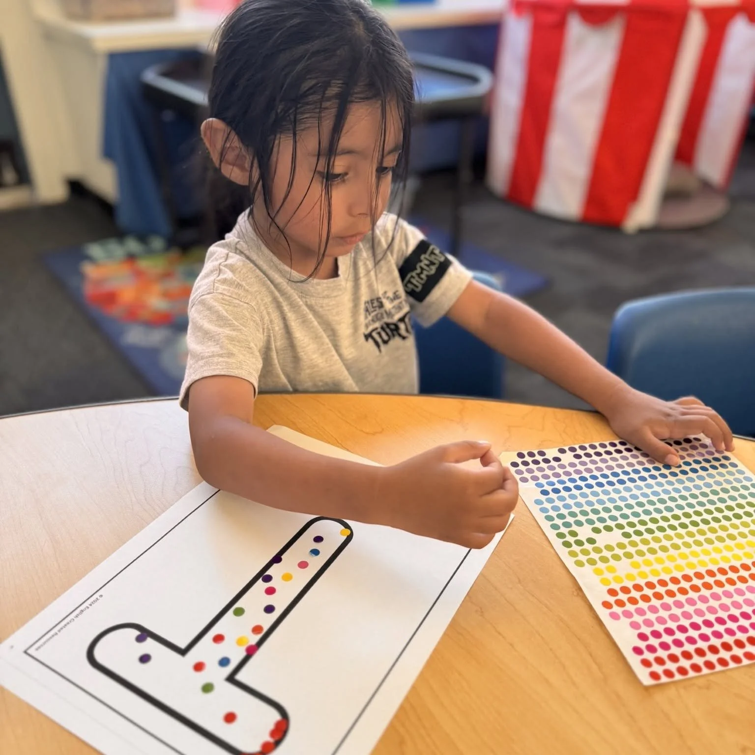 A student practices letter recognition by decorating a large T.