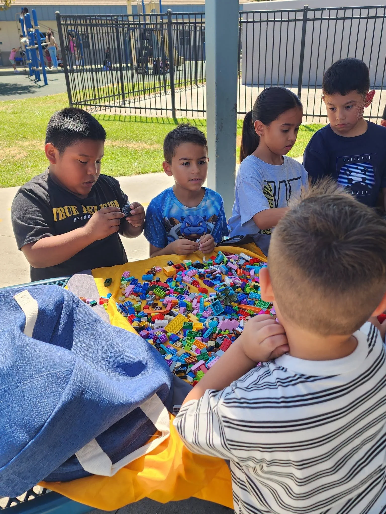 Students gather around a table of colorful Lego bricks.