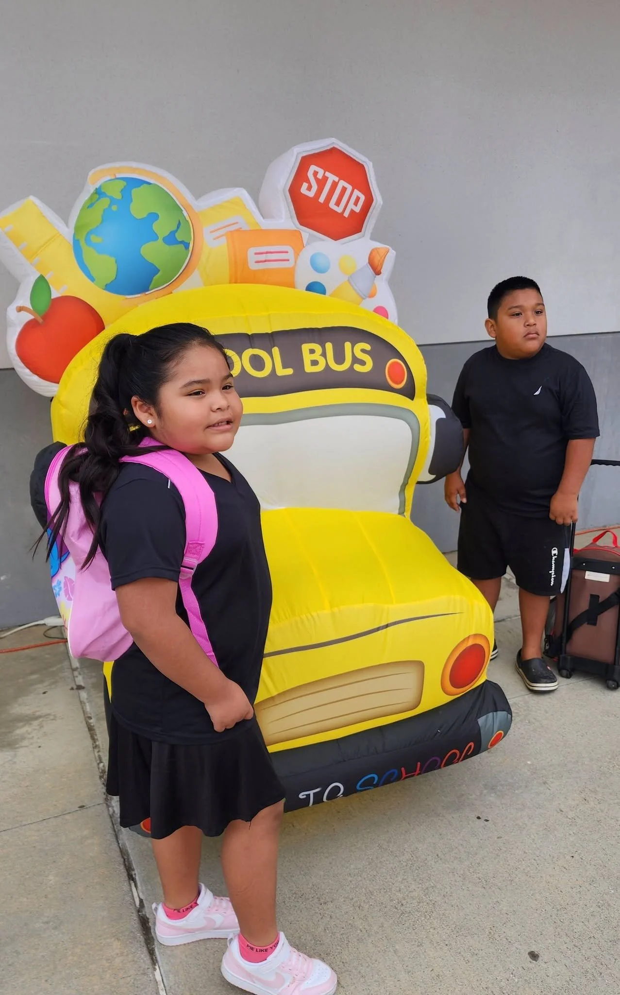 Two students pose on either side of the yellow school-bus display.