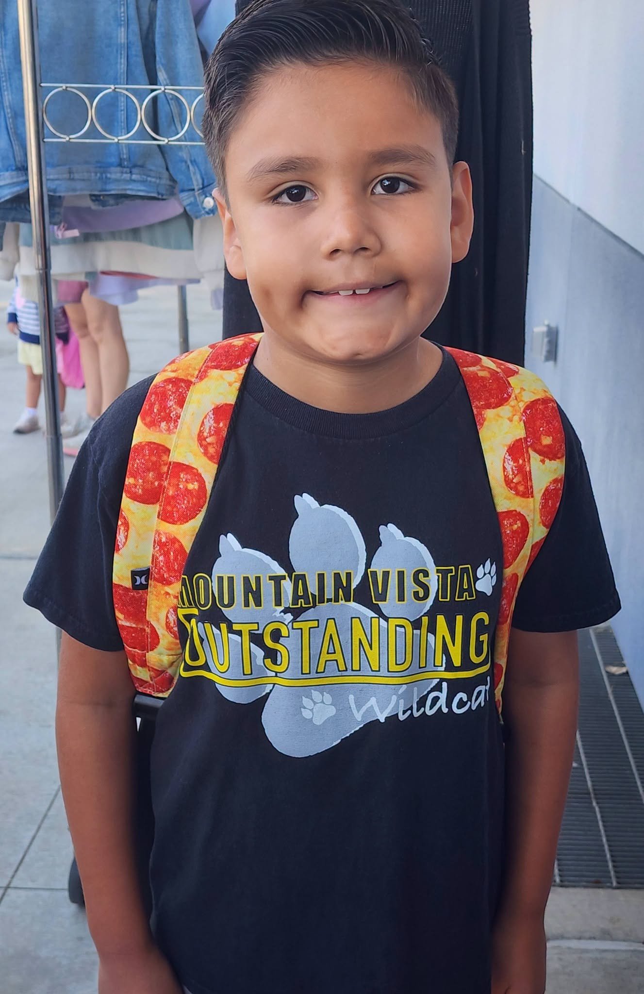 A student shows school spirit in an Outstanding Wildcat shirt and a pizza-patterned backpack.