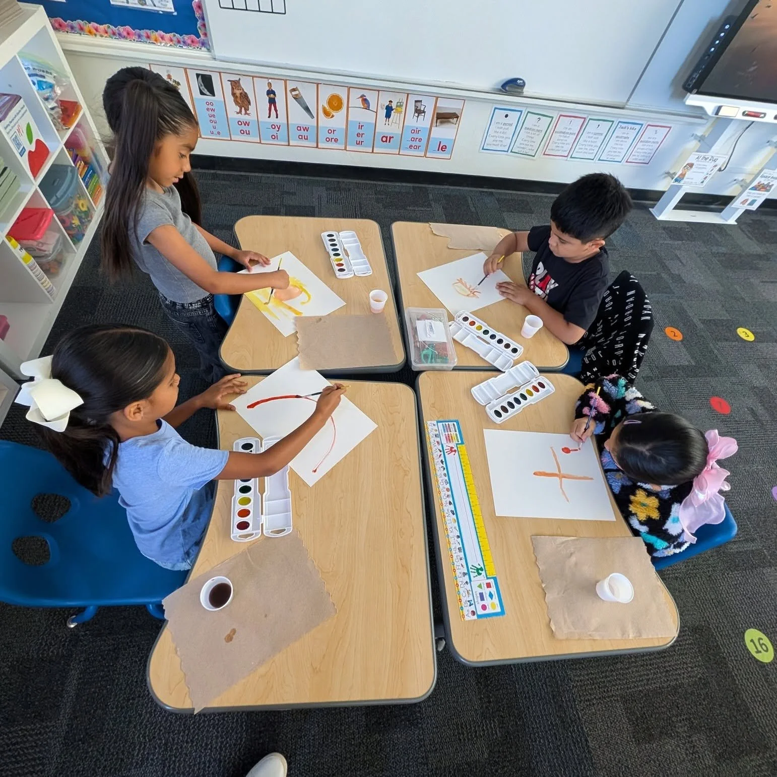 Students paint individual watercolor pictures at their desks.