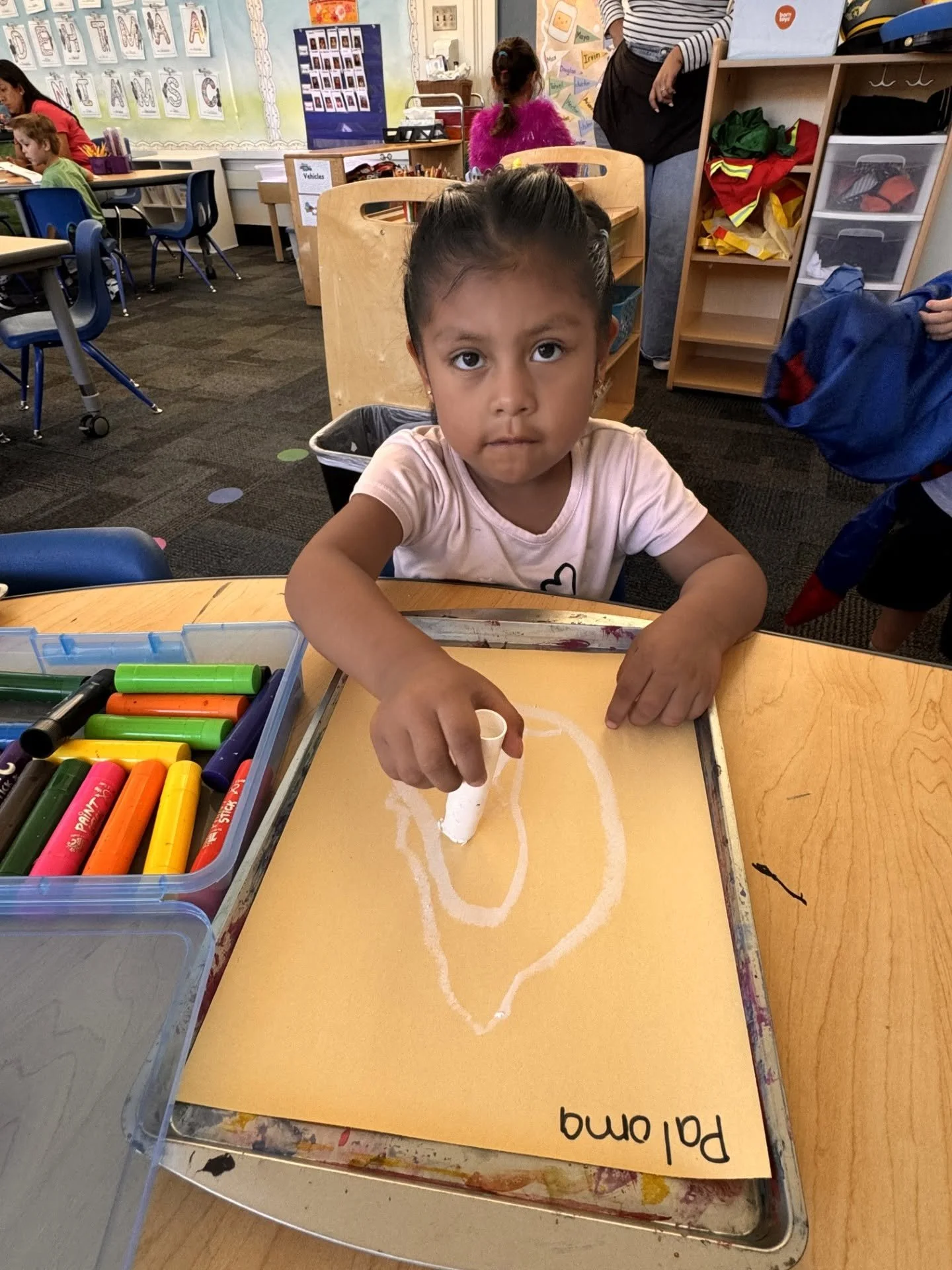 Student paints a white outline on paper during free-choice art time.