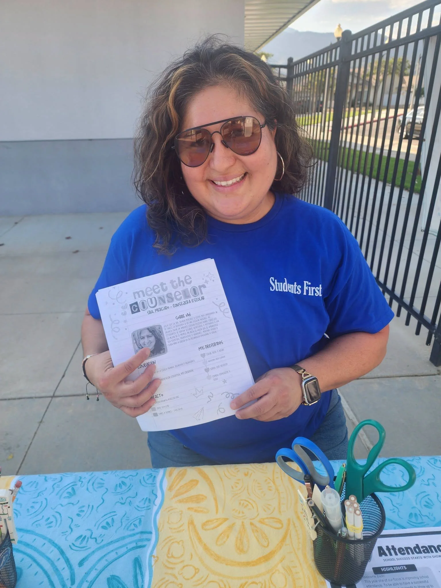 A school staff member shares a Meet the Counselor handout at the welcome table.