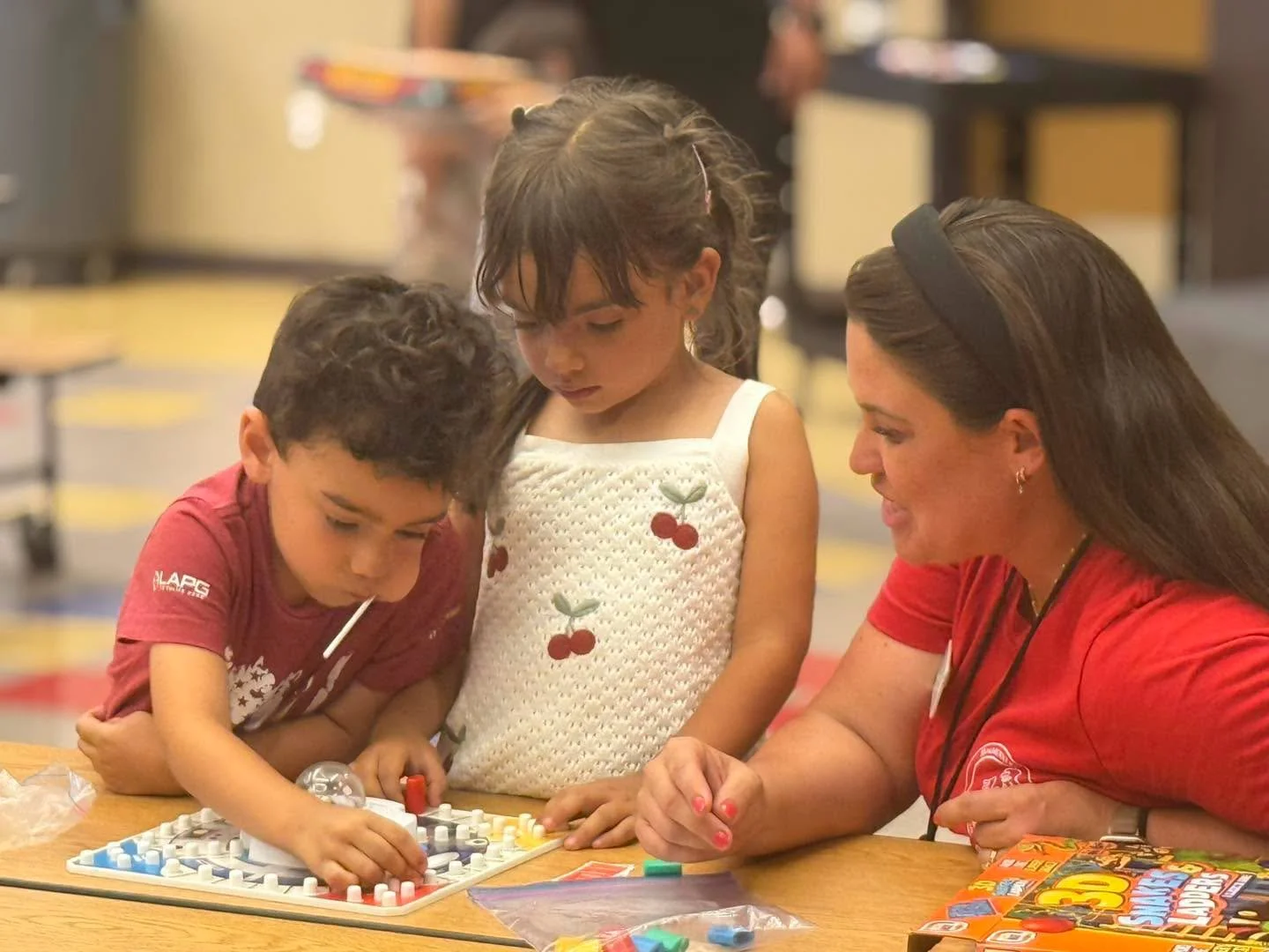 Two children and an adult play a board game together.