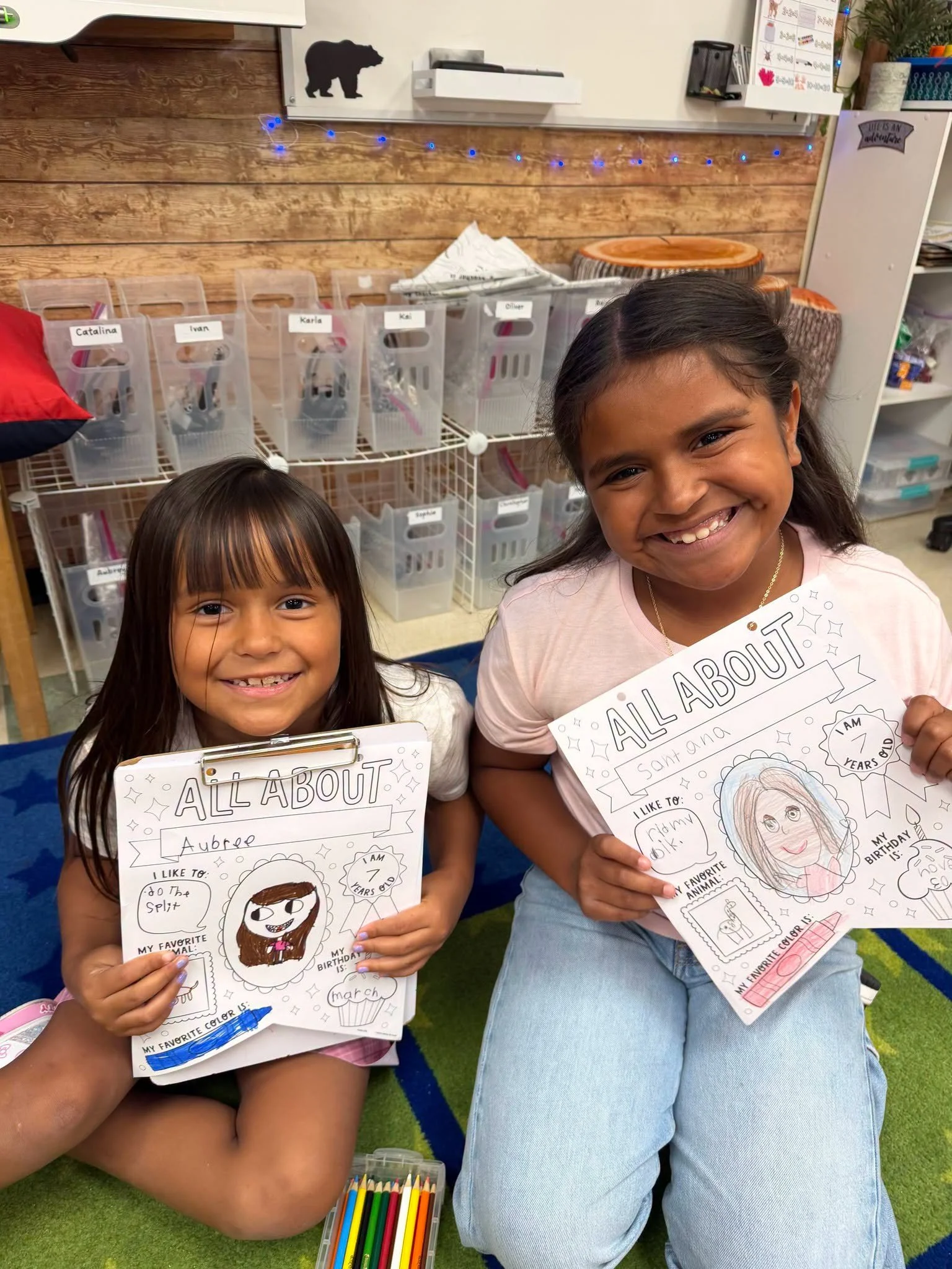 Two students display their illustrated All About Me worksheets.