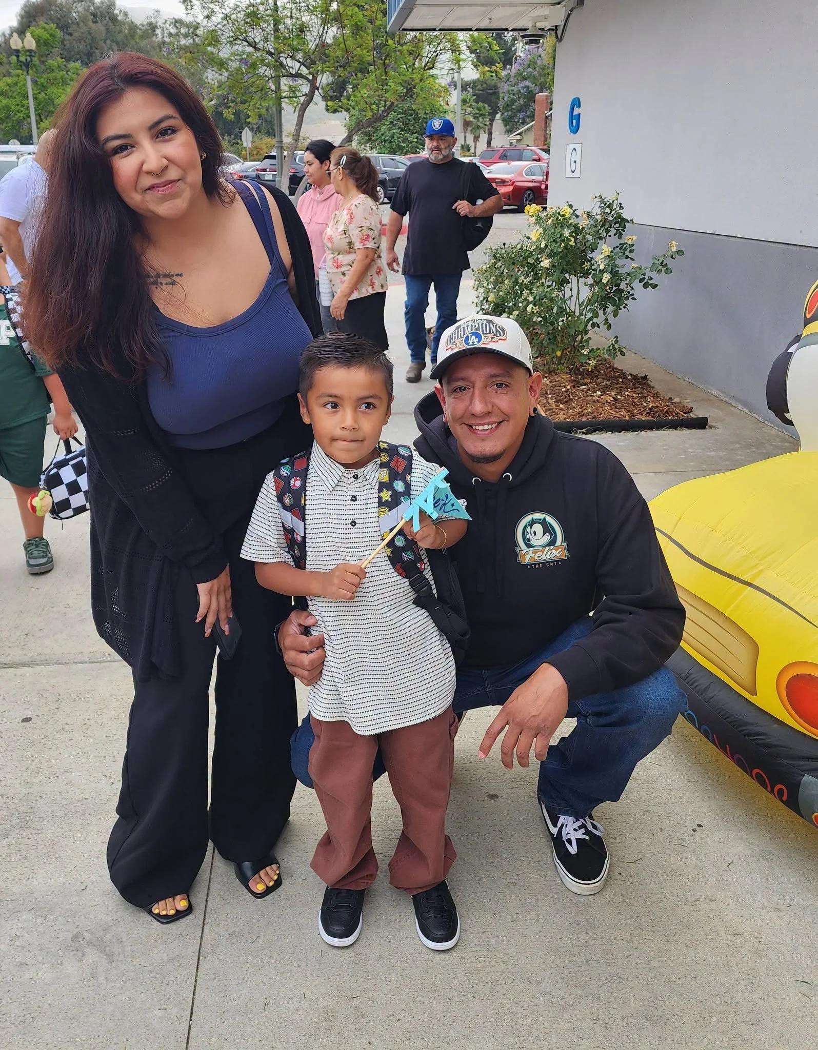 Two adults and a student pose together outside the school.