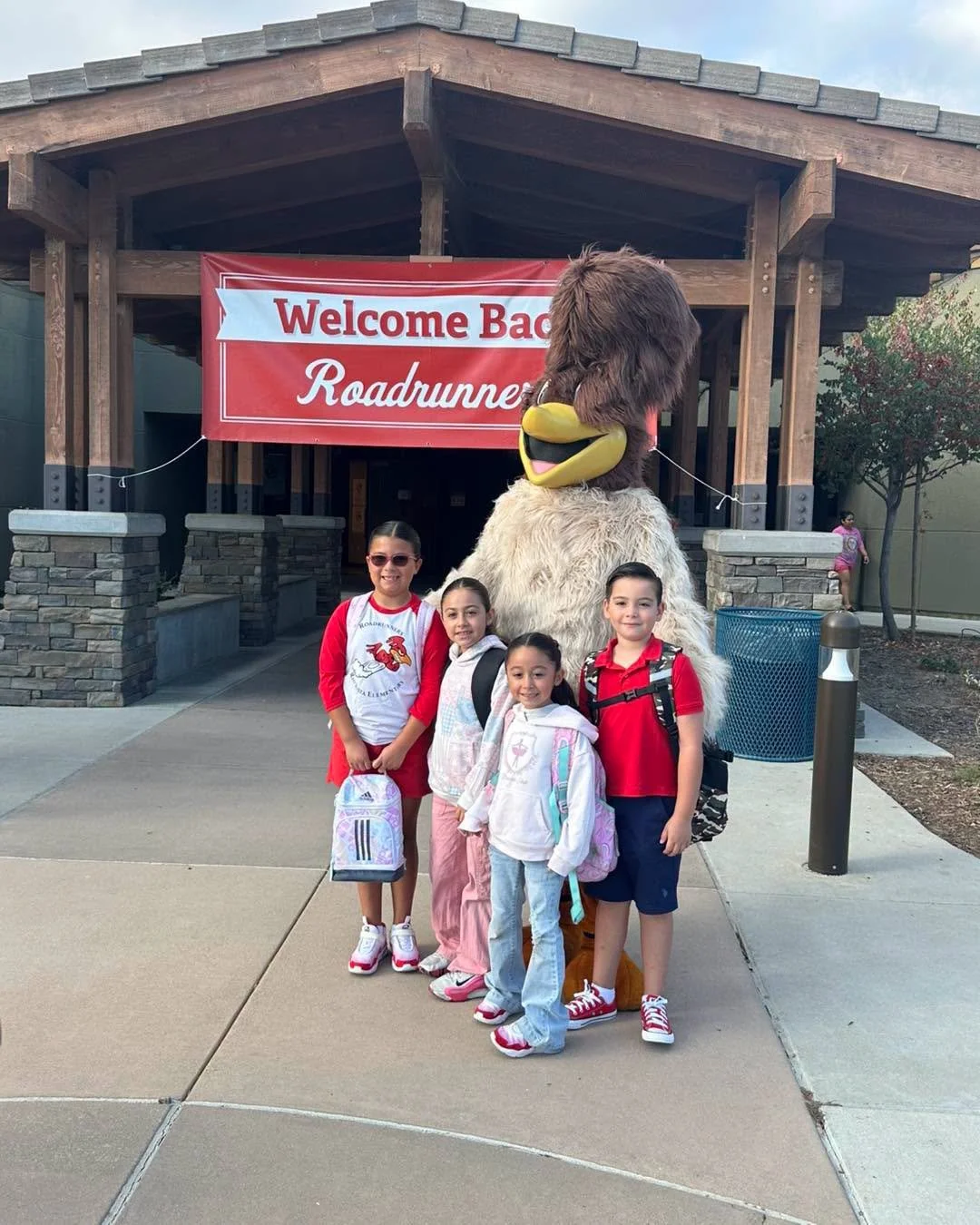 Students pose with Ronnie the Roadrunner beneath the welcome-back banner.