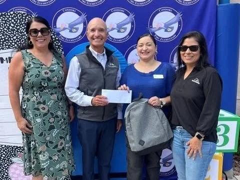 Community supporters present an envelope and backpack at Piru Elementary.